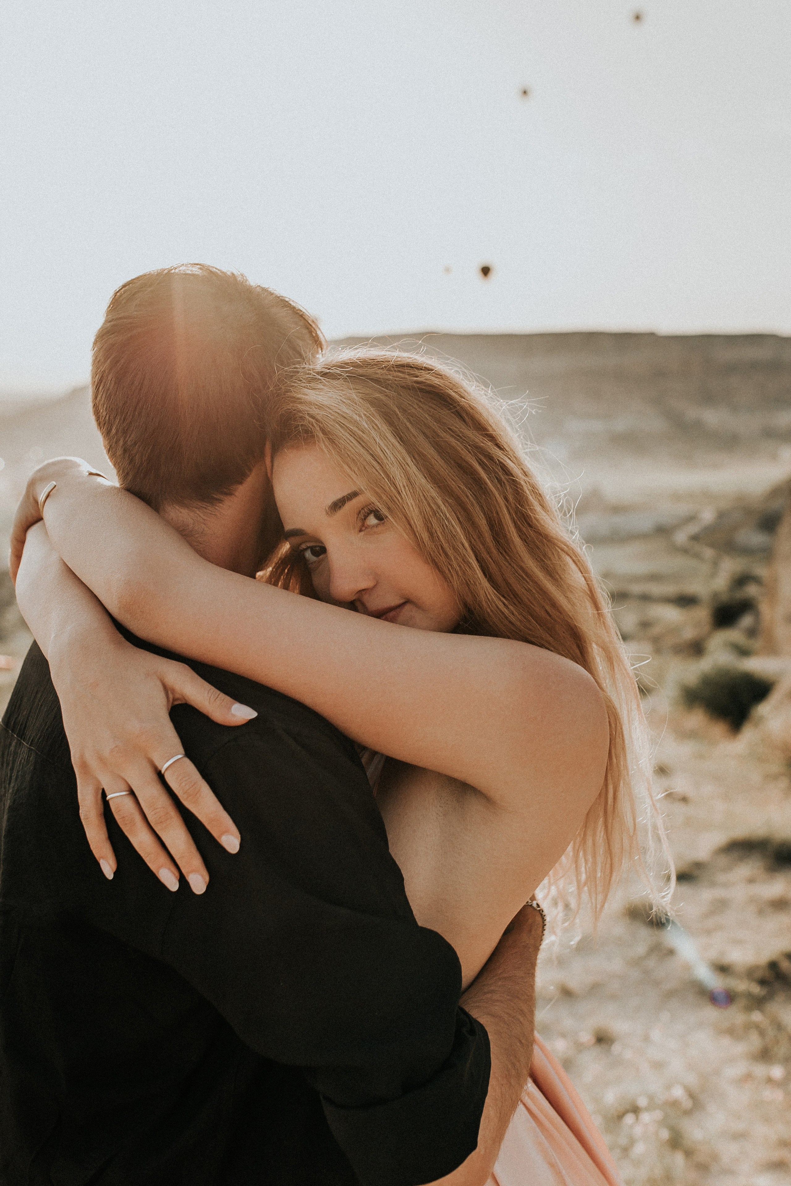 Paarfotografie beim Sonnenaufgang mit Heissluftballons im Hintergrund. Familien- & Hochzeitsfotografin Schweiz. Valeria Diaz in Zürich und Umgebung