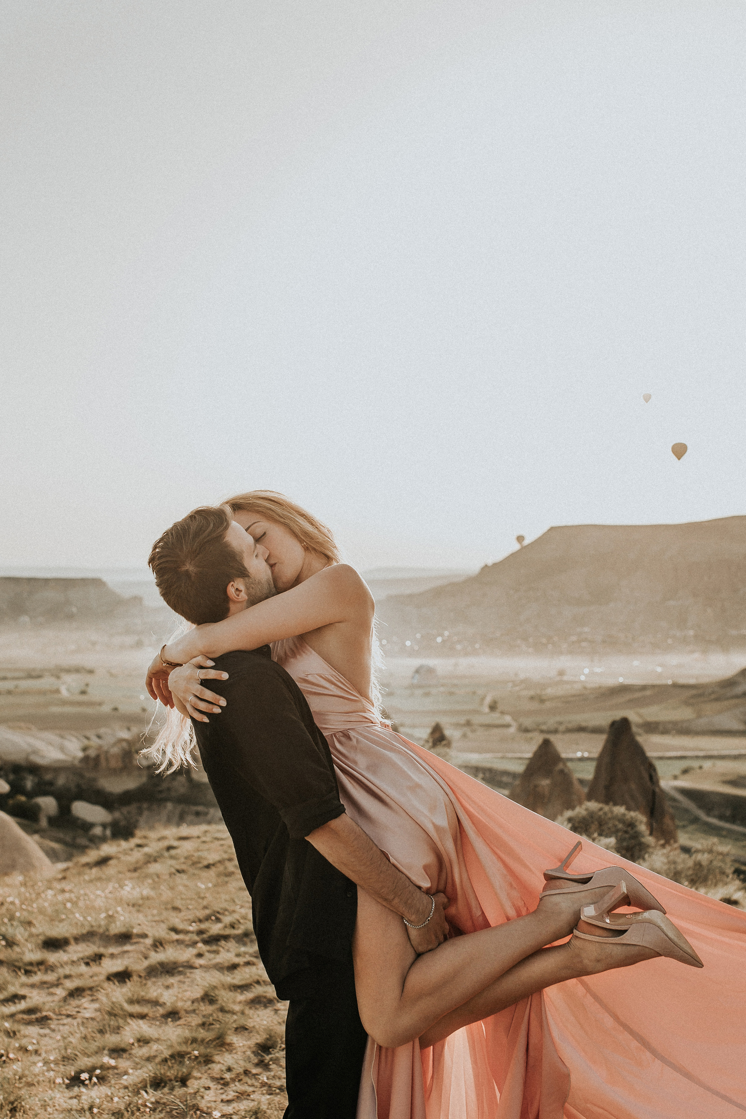 Paarfotografie beim Sonnenaufgang mit Heissluftballons im Hintergrund. Familien- & Hochzeitsfotografin Schweiz. Valeria Diaz in Zürich und Umgebung