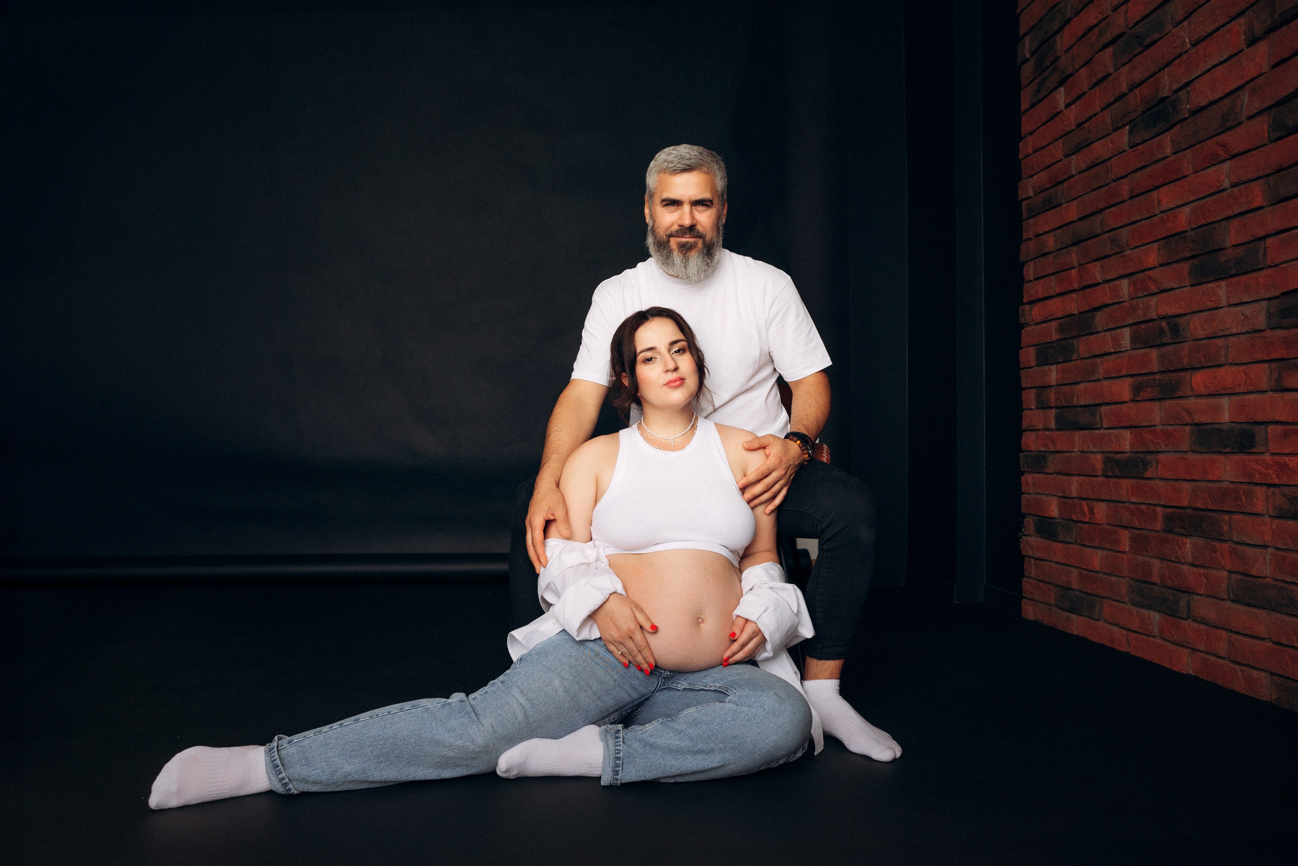 Sesja ciążowa dla par Szczecin – kobieta siedzi między nogami partnera, gest bliskości i bezpieczeństwa, studio Prostir.