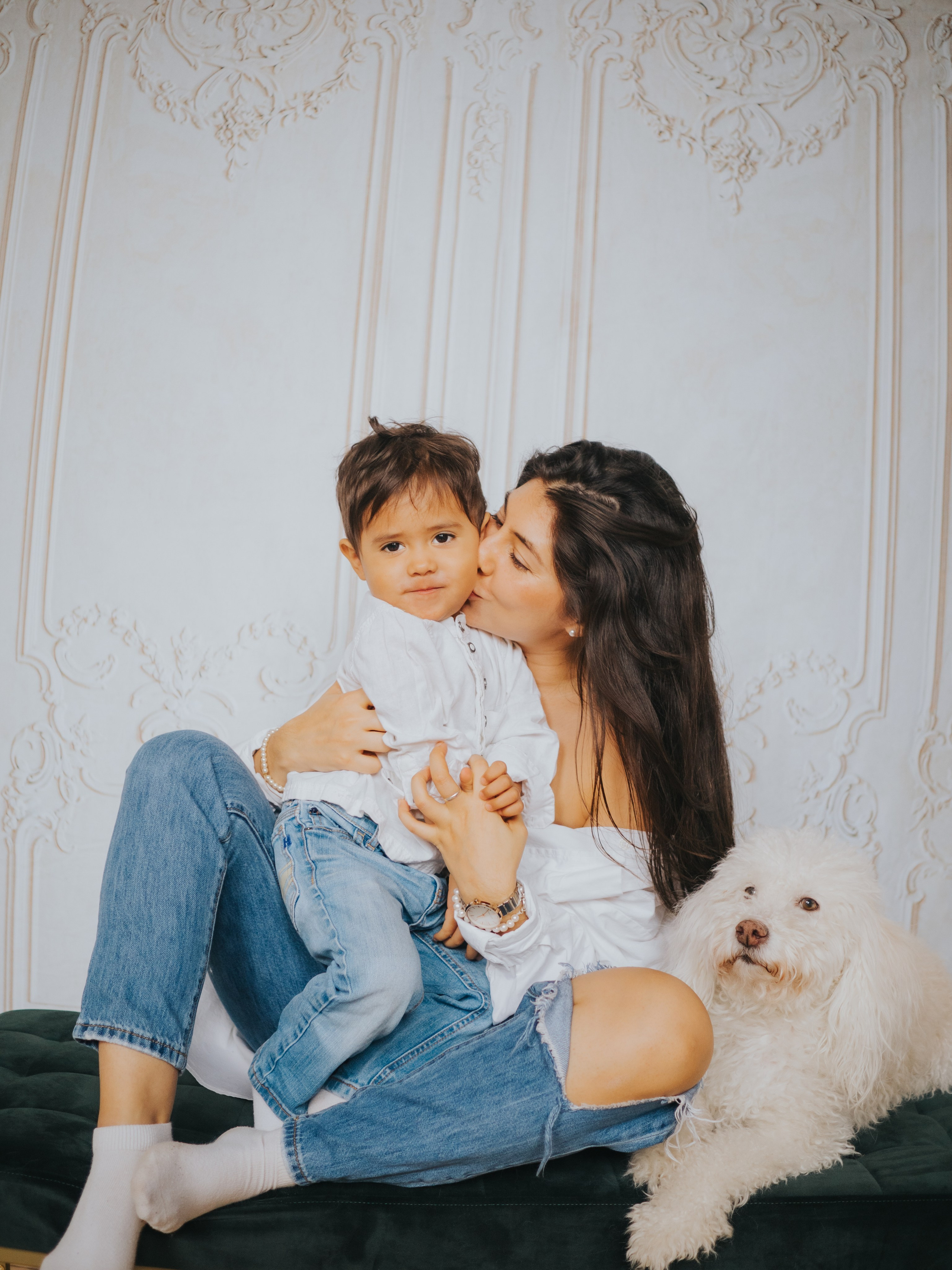 Mom, son, and dog in front of a wall with moldings.