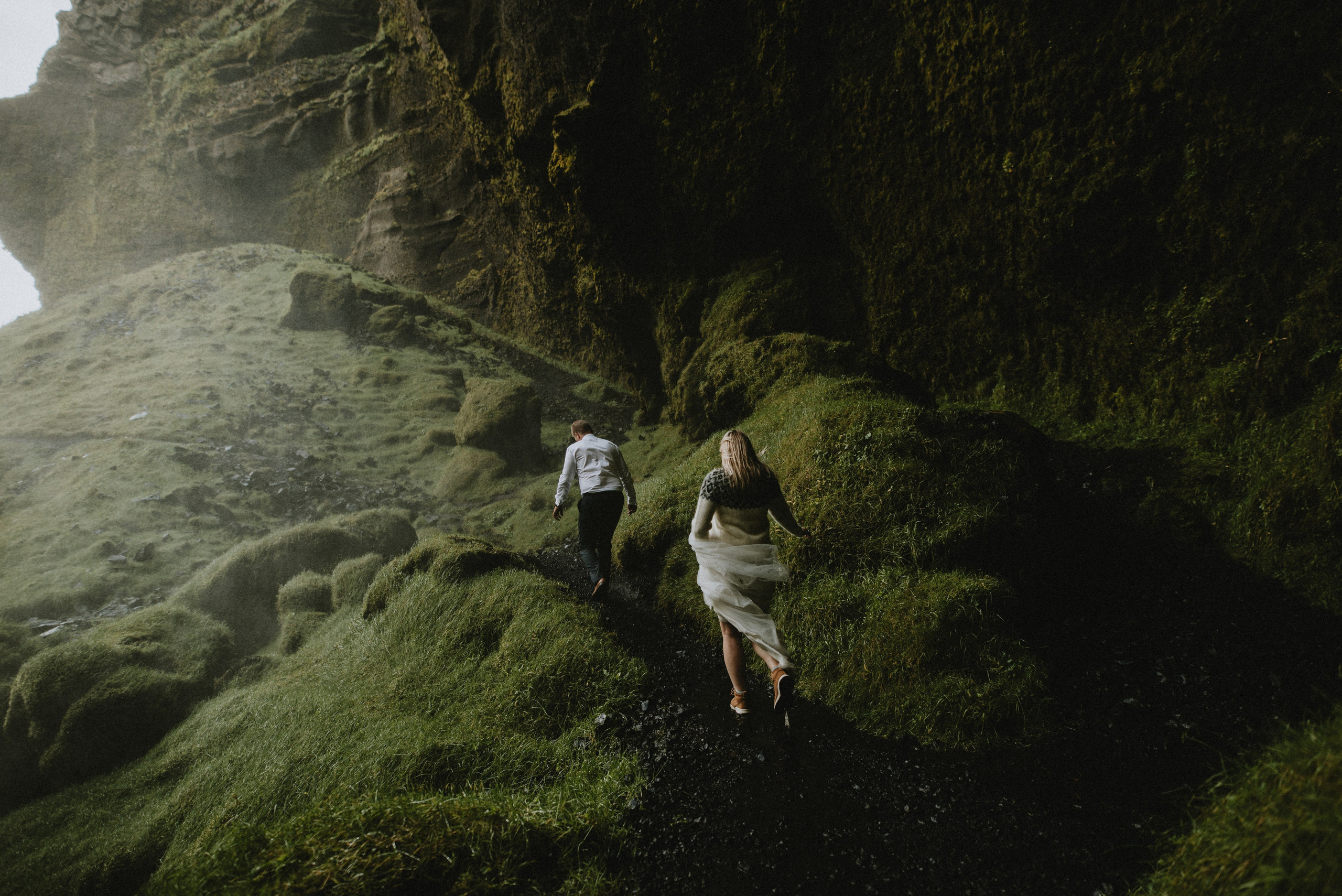 Eloping couple exploring the lush green canyon near Kvernufoss, surrounded by untouched Icelandic nature.