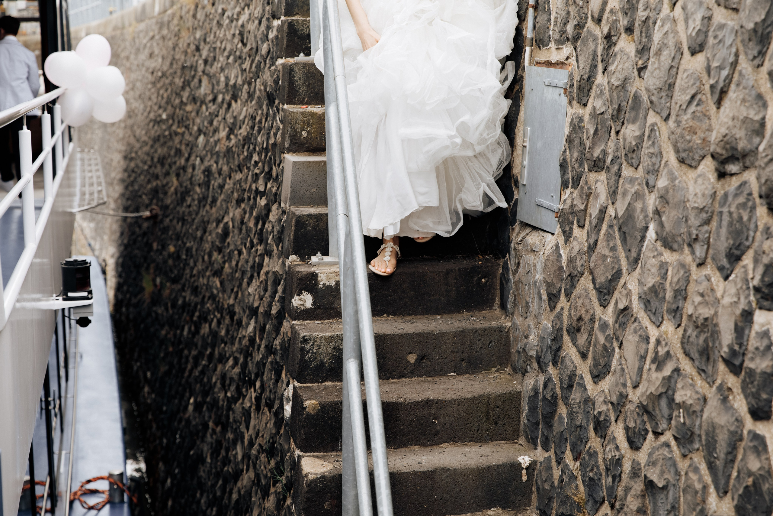 Die Fußsohle der Braut in Sandalen, die die Treppe hinuntersteigt, um zum Schiff zu gelangen.