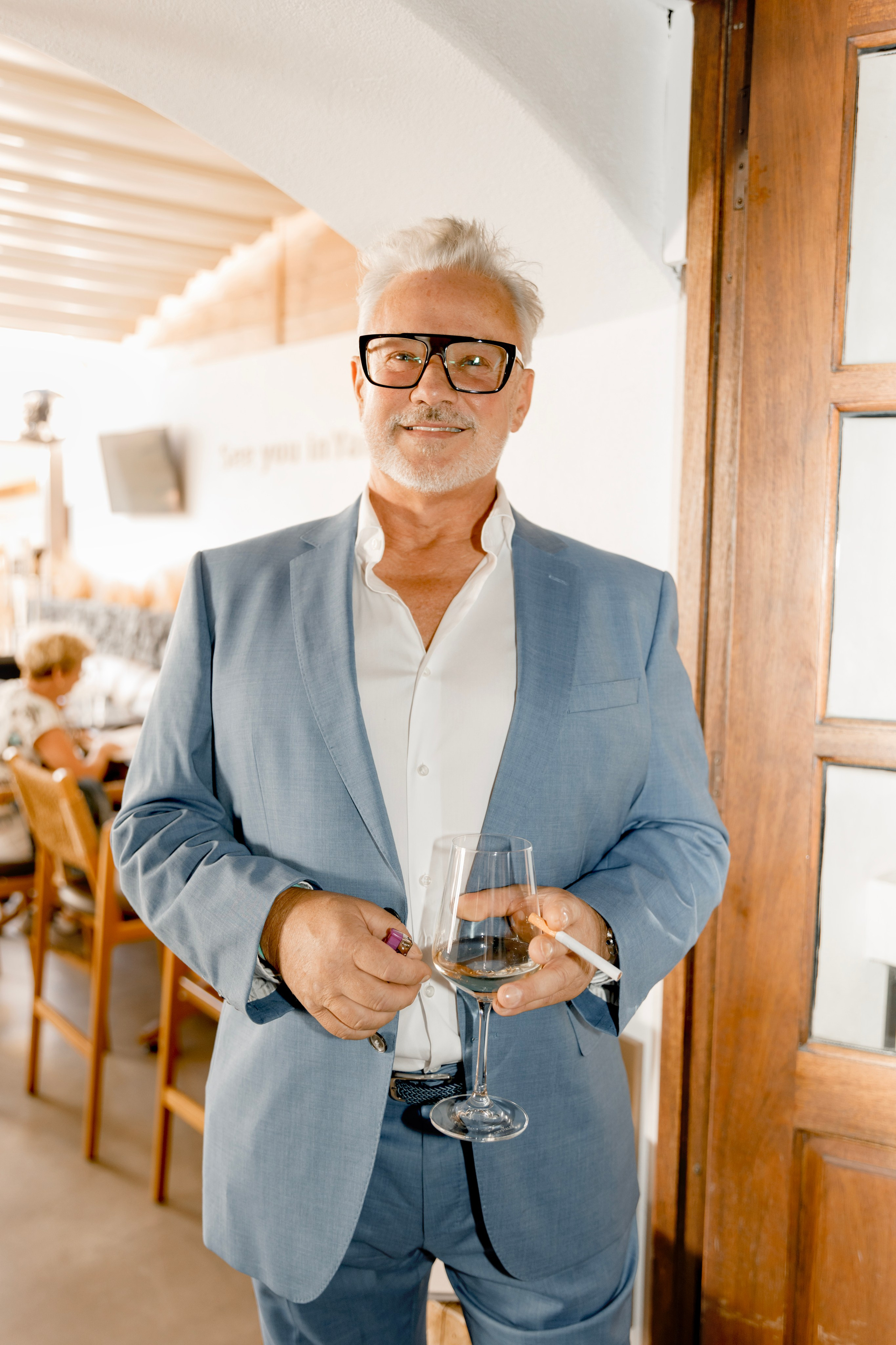 Groom's friend is posing for a photo at a pre-wedding party in a traditional Greek bar in Lindos