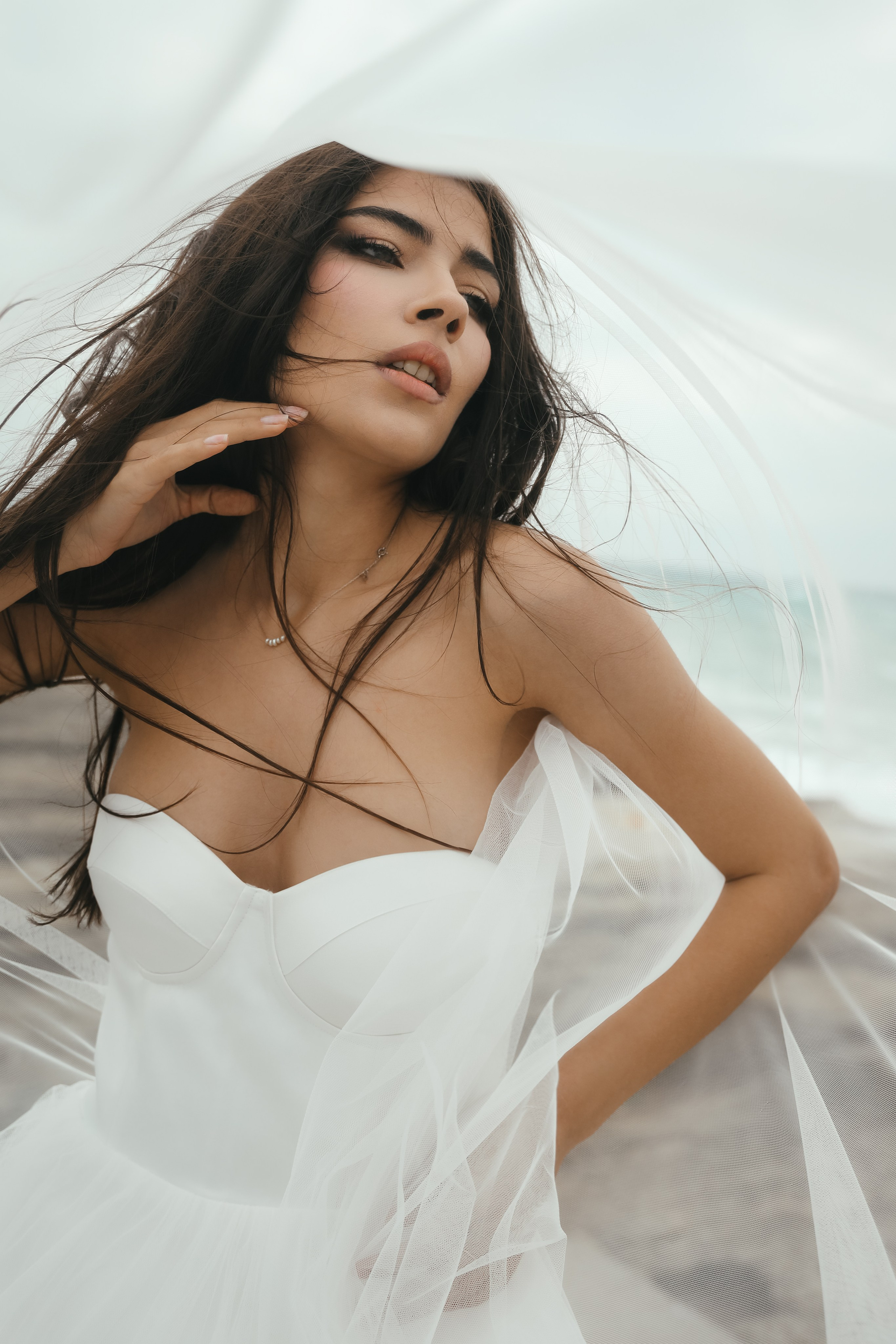 An art photo shoot of a girl in a wedding dress on the windy Kalithea beach in Rhodes, Greece