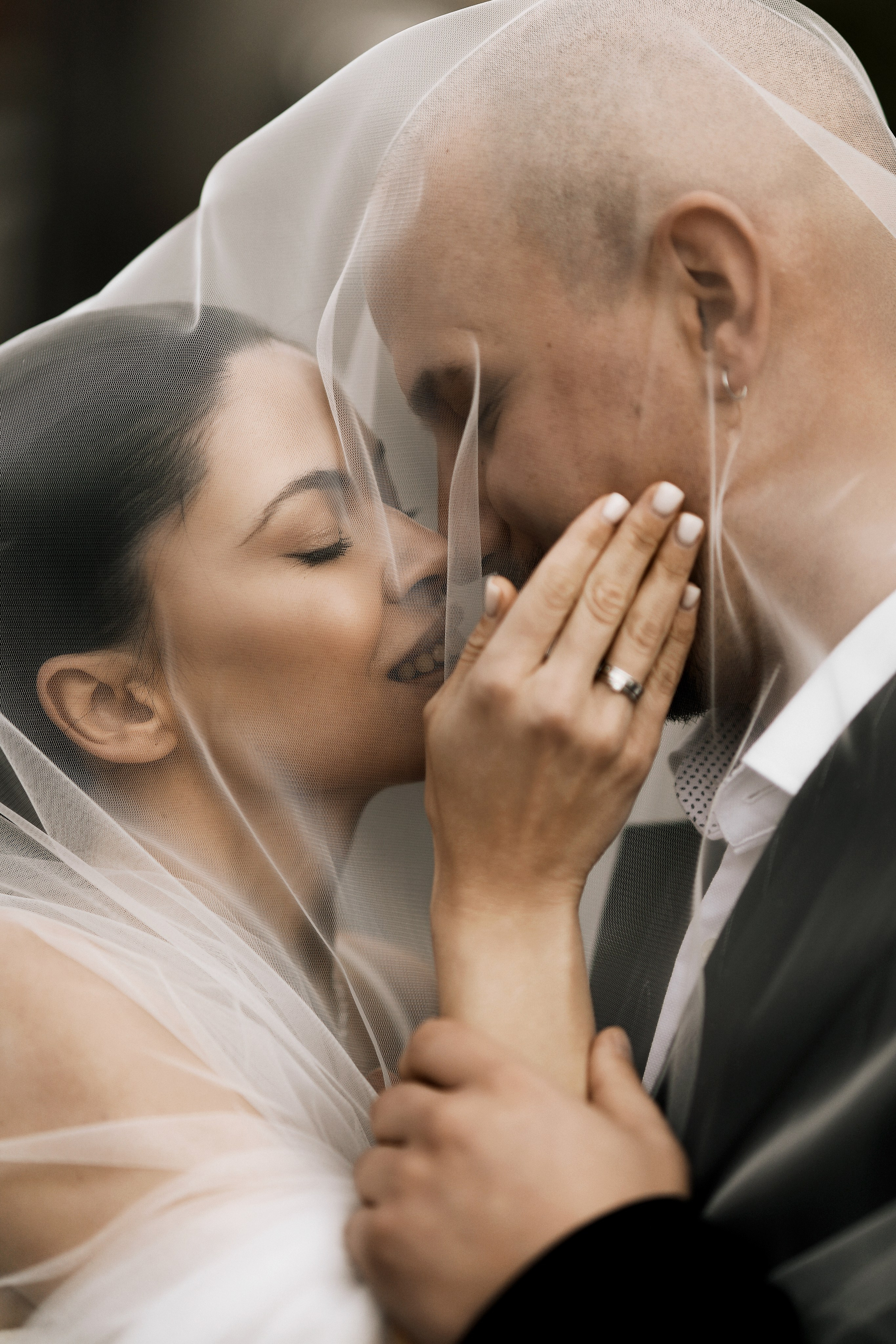 Bride and groom close-up under veil during emotional wedding moment