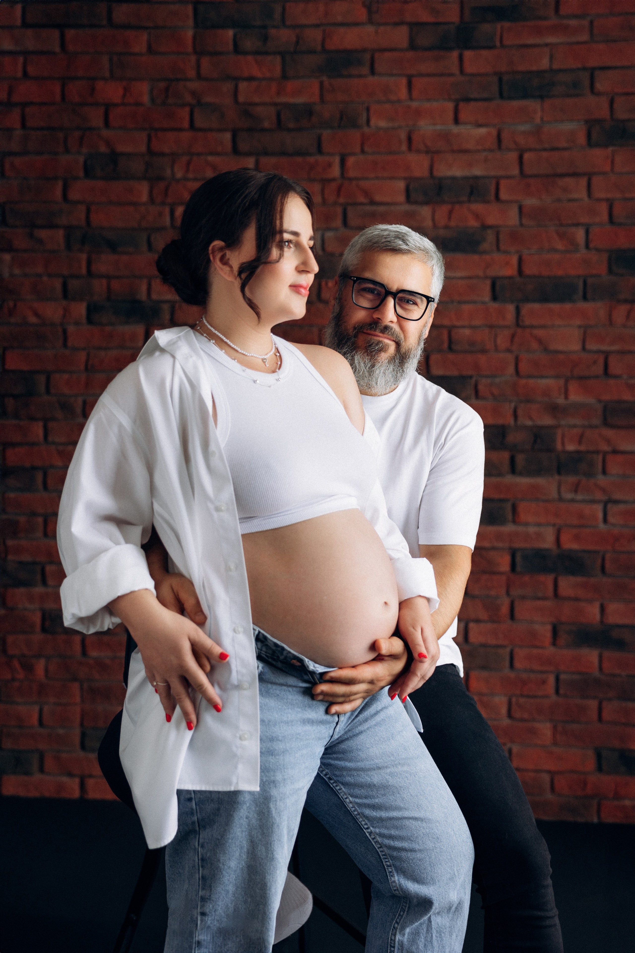  Sesja ciążowa dla par Szczecin – przyszli rodzice w objęciach na ciemnym tle, emocjonalna fotografia w studio Prostir. Couple maternity session Szczecin – expecting parents embracing on a dark background, emotional studio photography at Prostir.