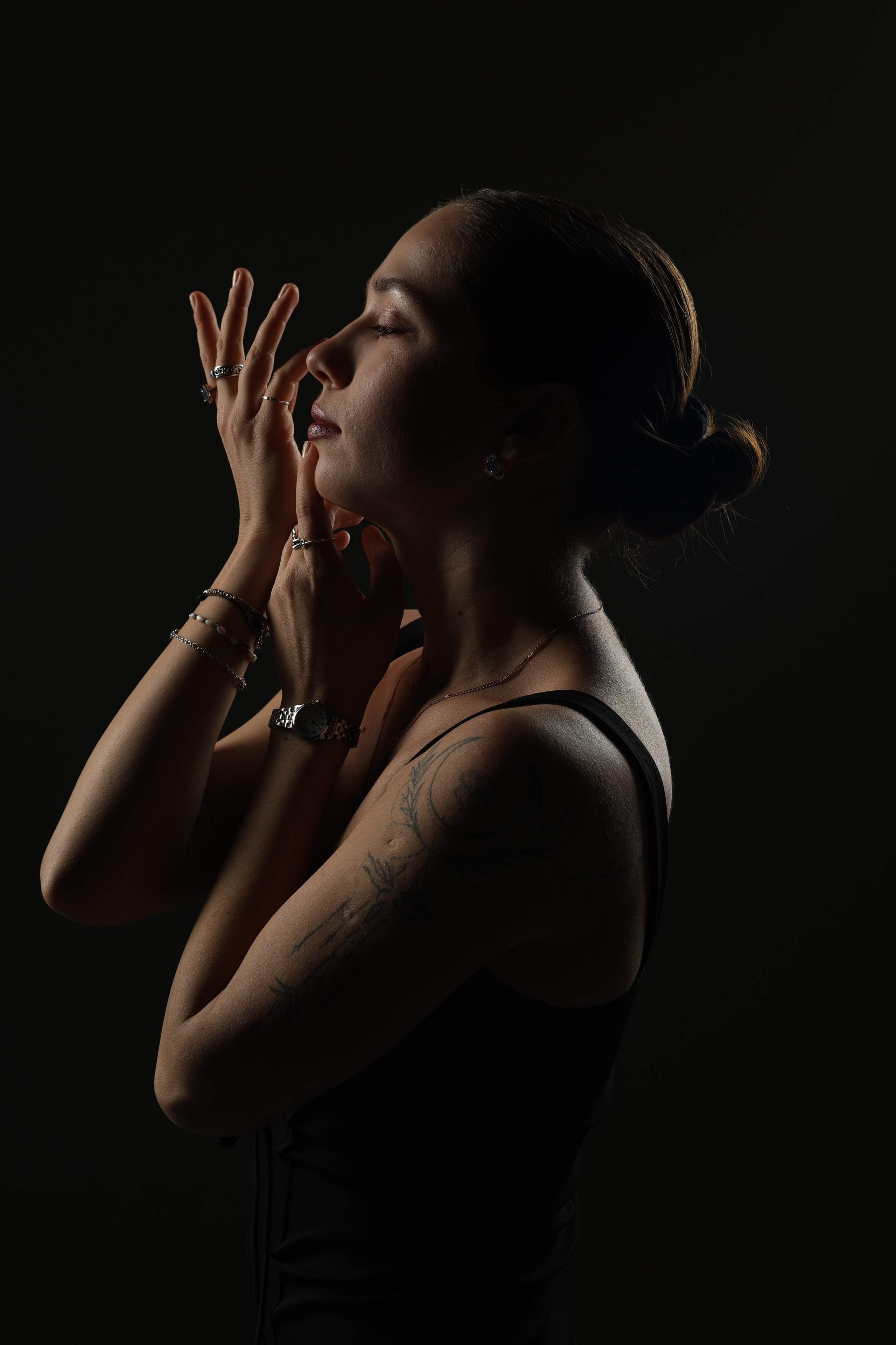 Девушка позирует в студии, низкий ключ, игра света подчёркивает черты лица