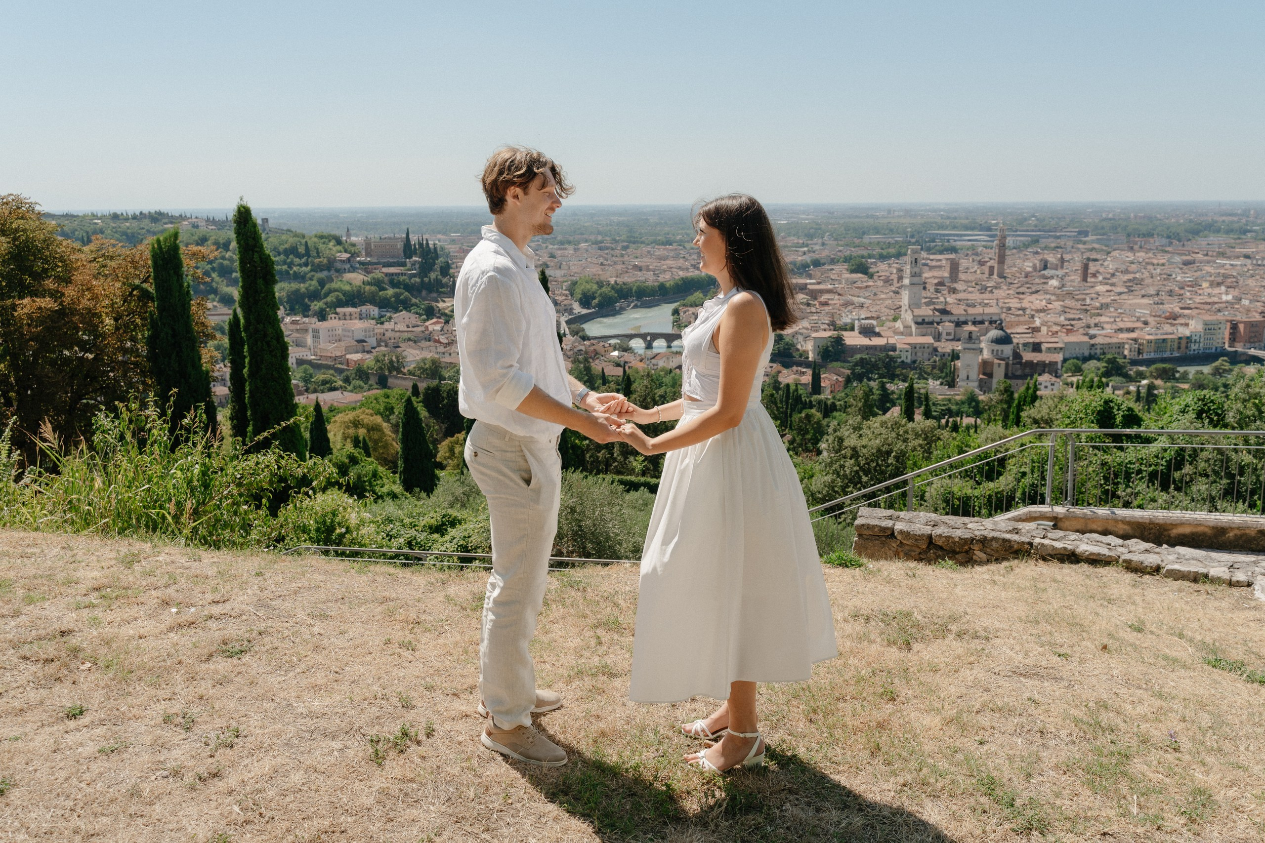 Happy couple celebrating their engagement while overlooking the beautiful city of Verona.