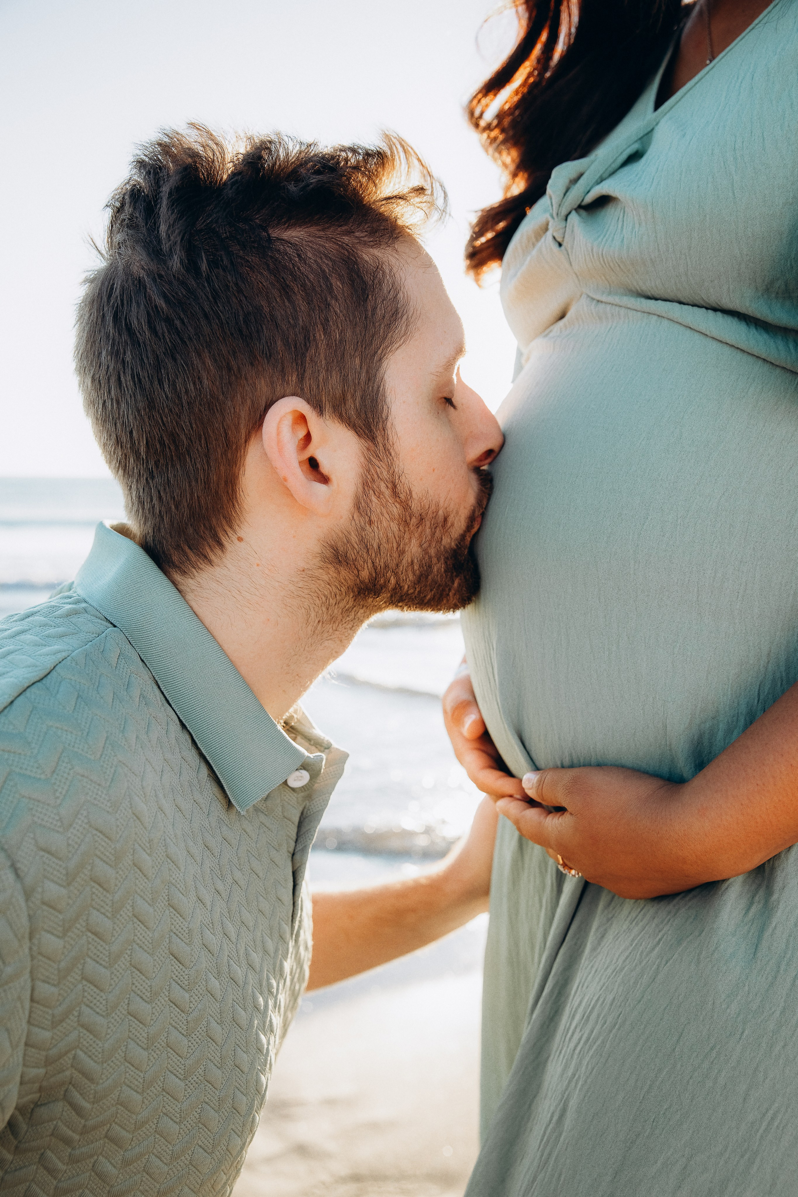Sesión de fotos de maternidad emotiva en Valencia, España, que refleja un momento tierno cuando el futuro padre besa la barriga de su pareja embarazada — ideal para parejas que buscan sesiones de embarazo íntimas y llenas de sentimiento en Valencia y en toda España.