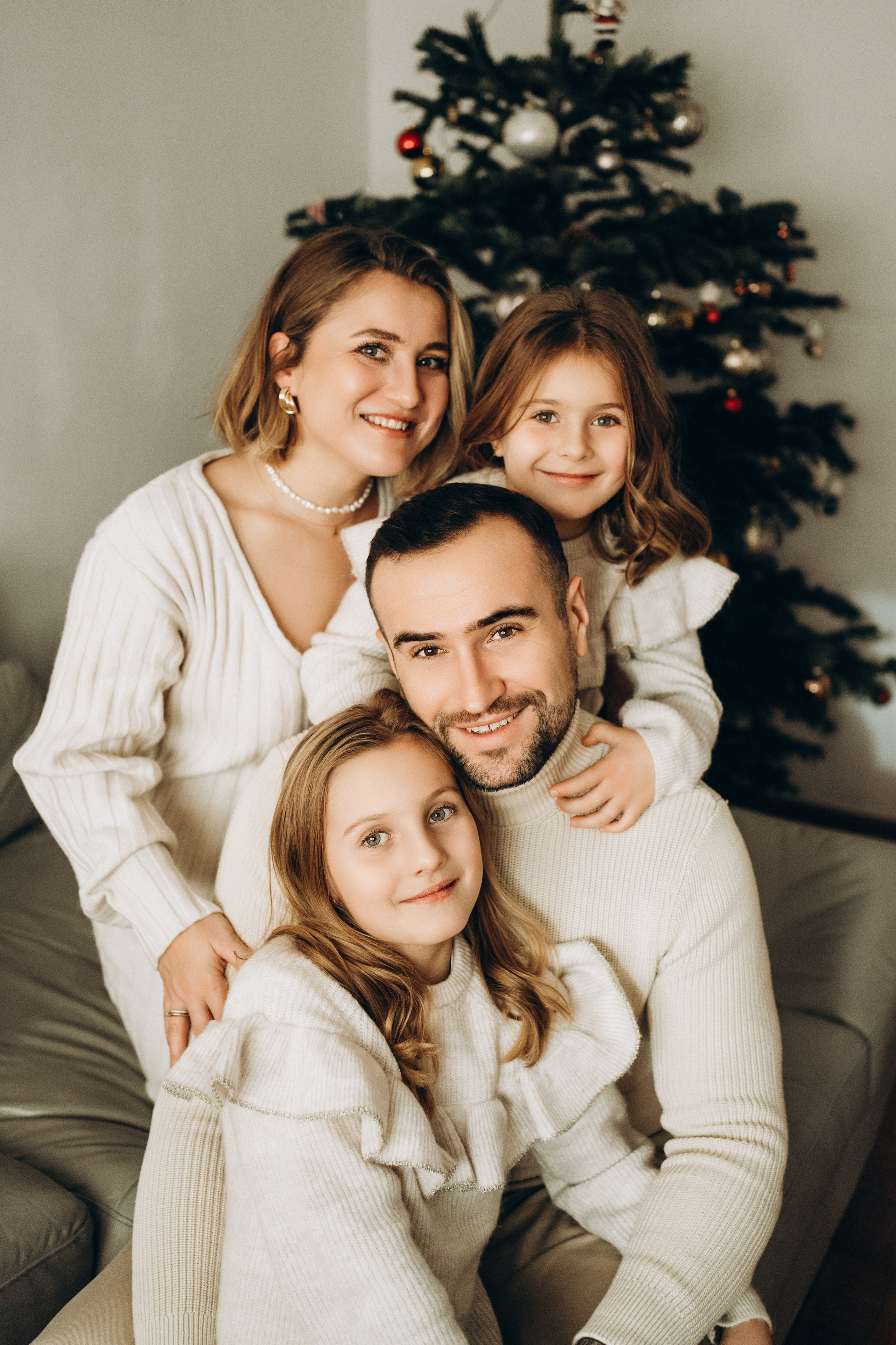 Wunderschöne Portraits einer stylisch gekleideter Familie vor dem Weihnachtsbaum.