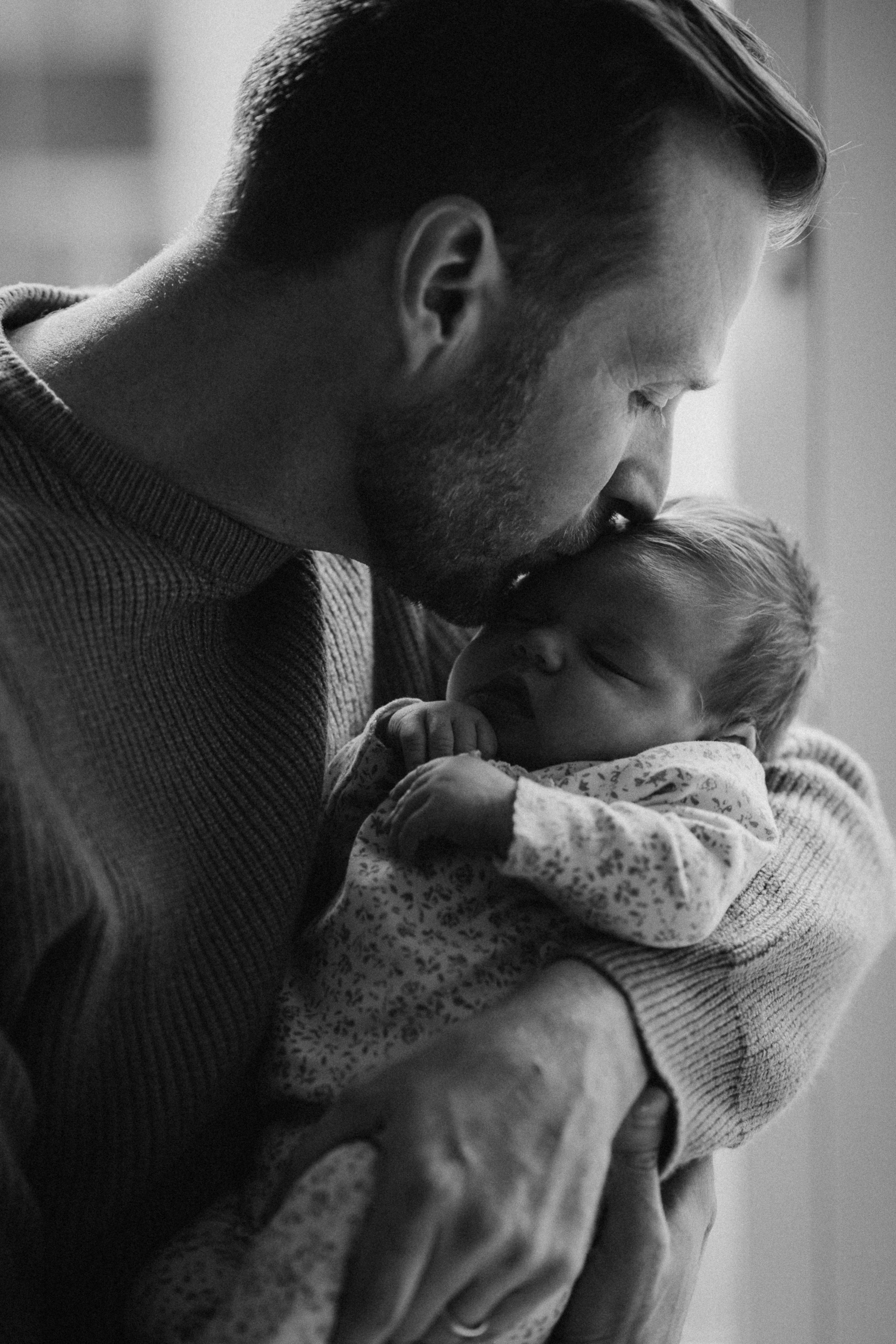 dad kissing his newborn baby