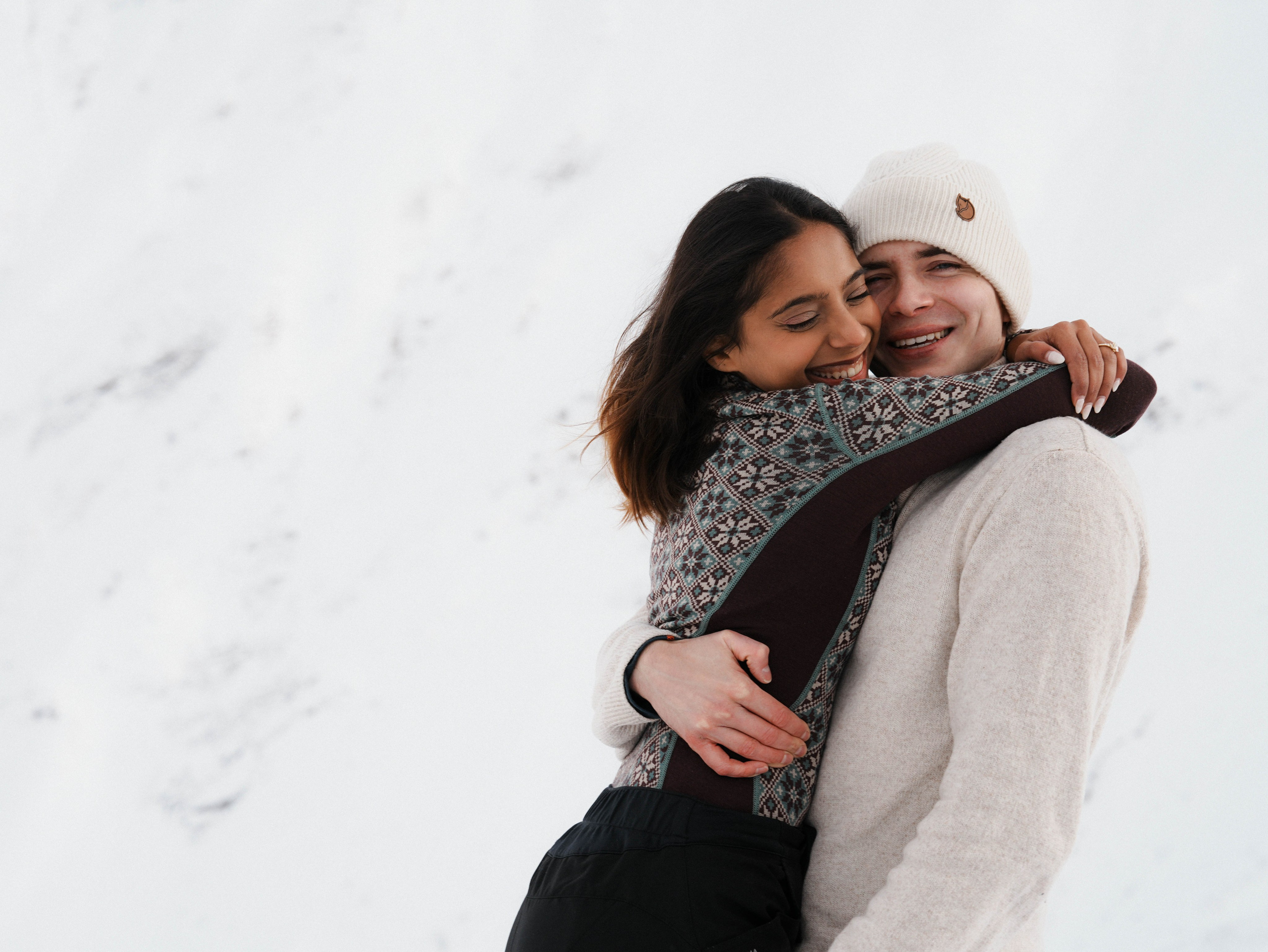 Couple embracing after proposal in snowy mountains