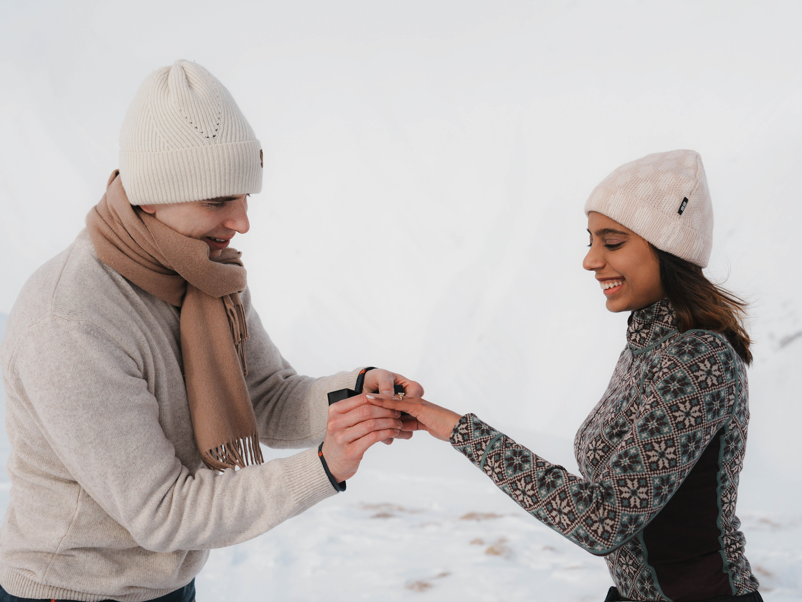 Man putting engagement ring during proposal in mountains