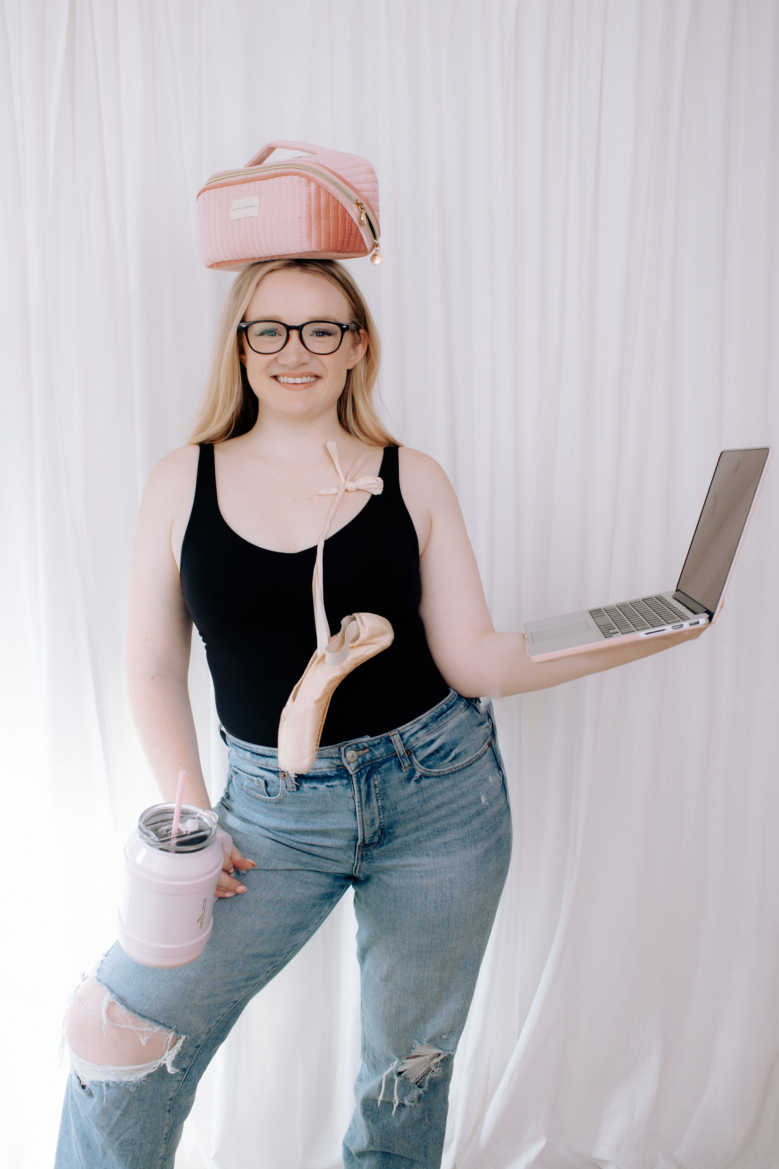 Brand photo of a dance teacher holding a laptop, ballet shoes and water bottle