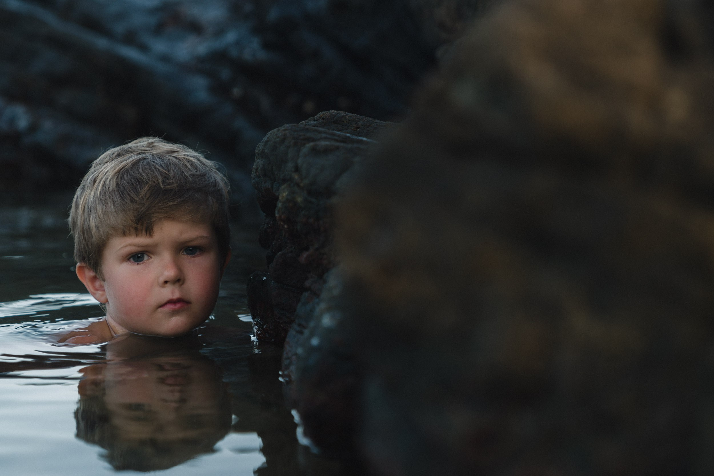 dramatic portrait of the boy in the water and rocks 