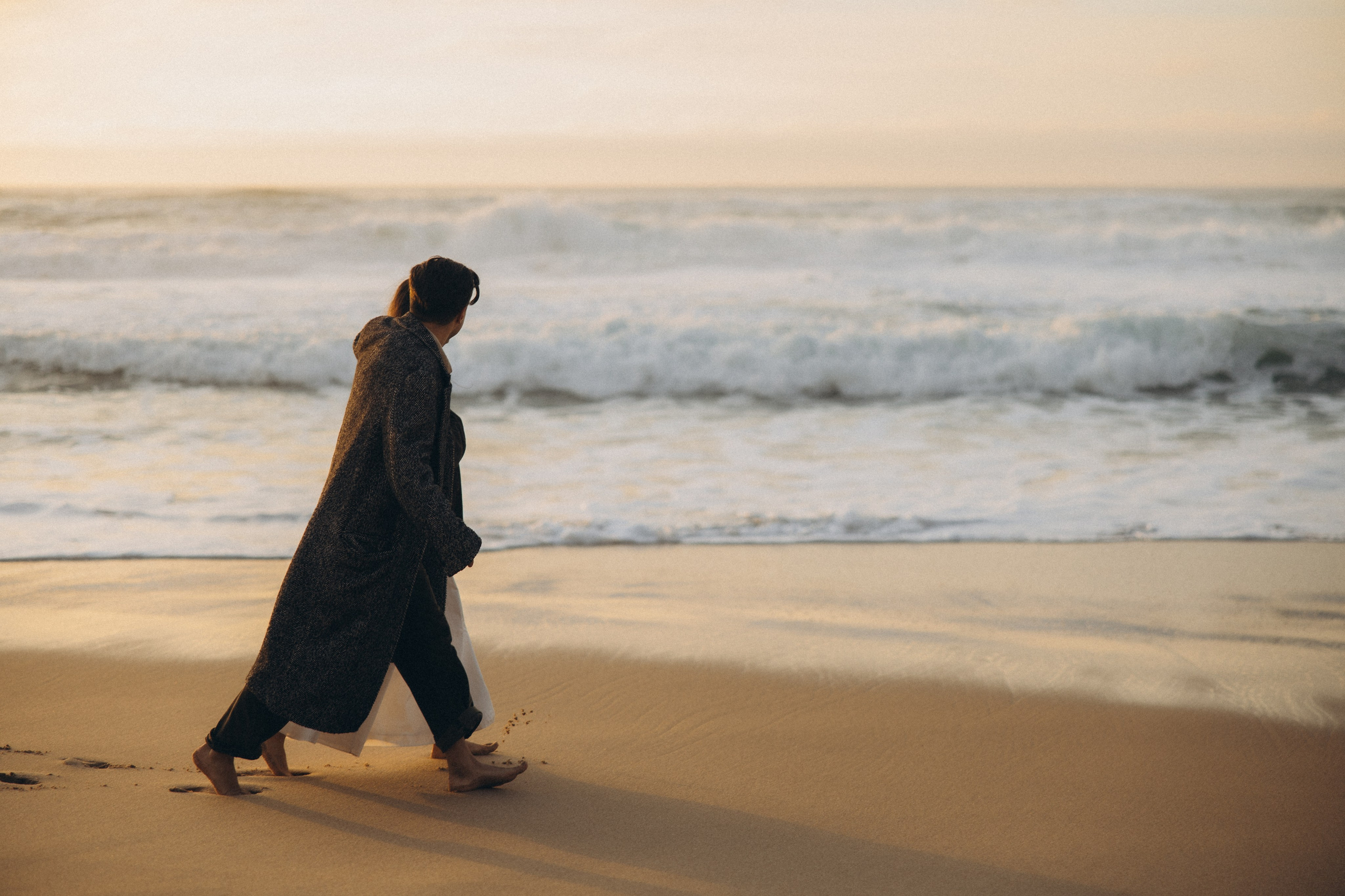 Couple holding hands and walking through a picturesque coastline in Portugal.