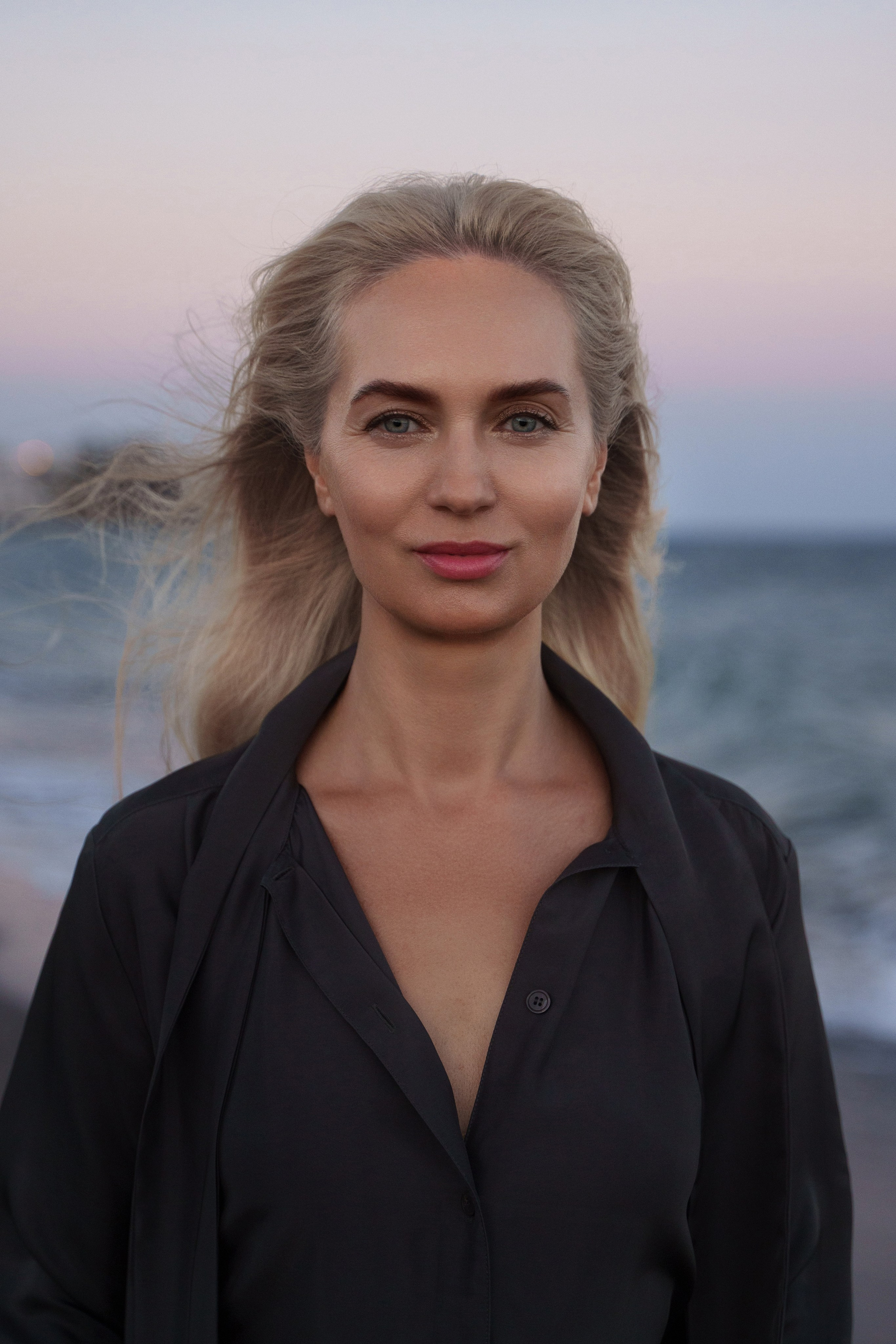 Elegant blonde woman posing near the shoreline of Estepona beach, photographed by a female photographer