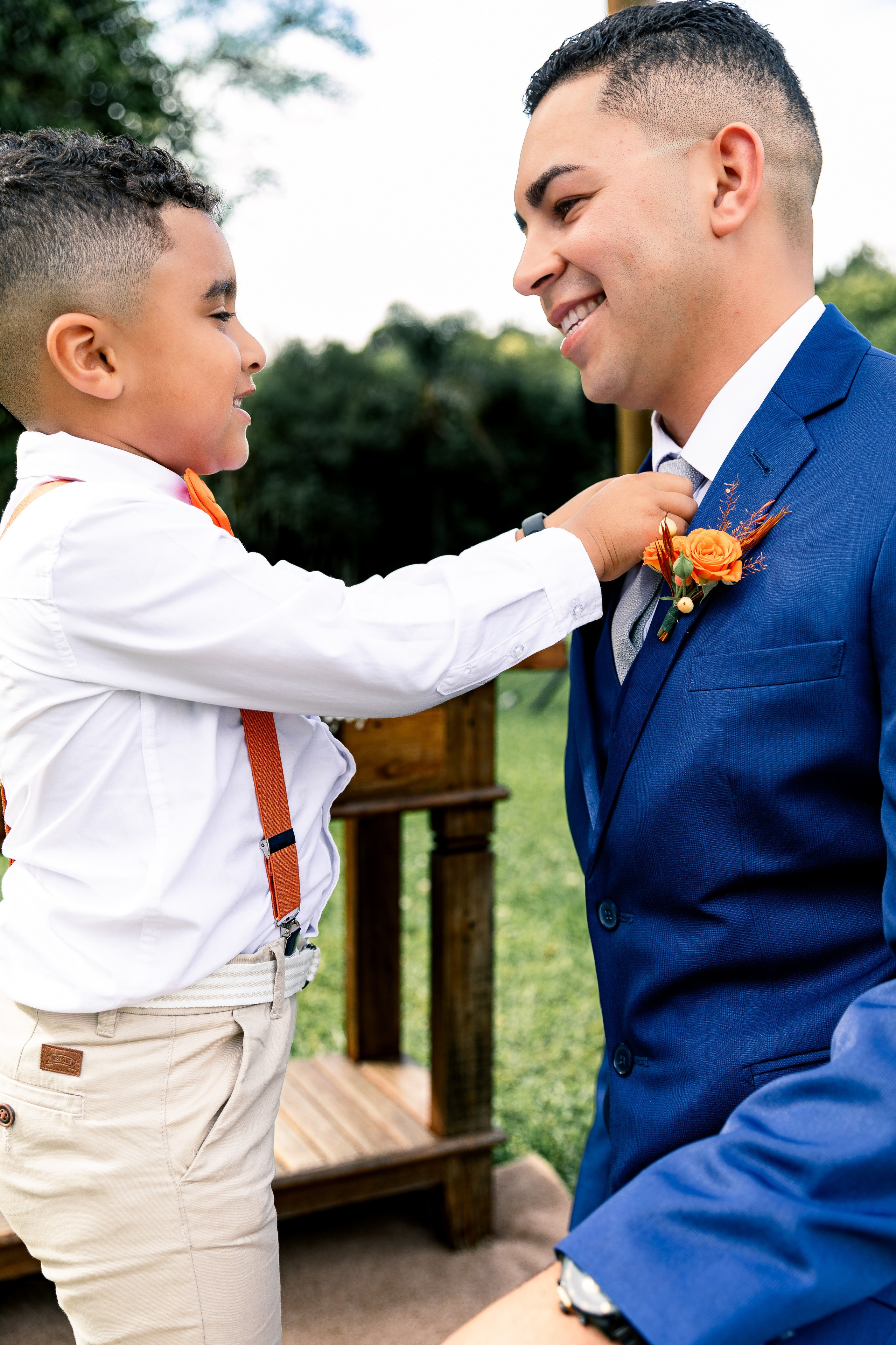 Noivo olhando para o seu filho enquanto ele arruma a gola da camisa
