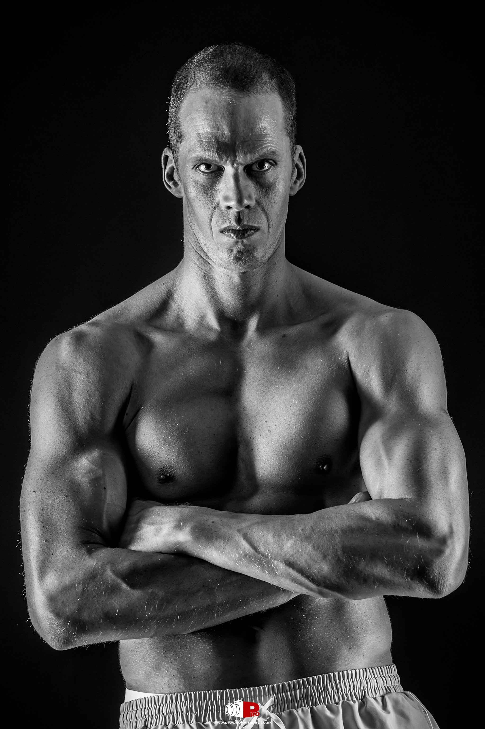 Black and white fitness portrait of a determined male model with a strong, muscular upper body.