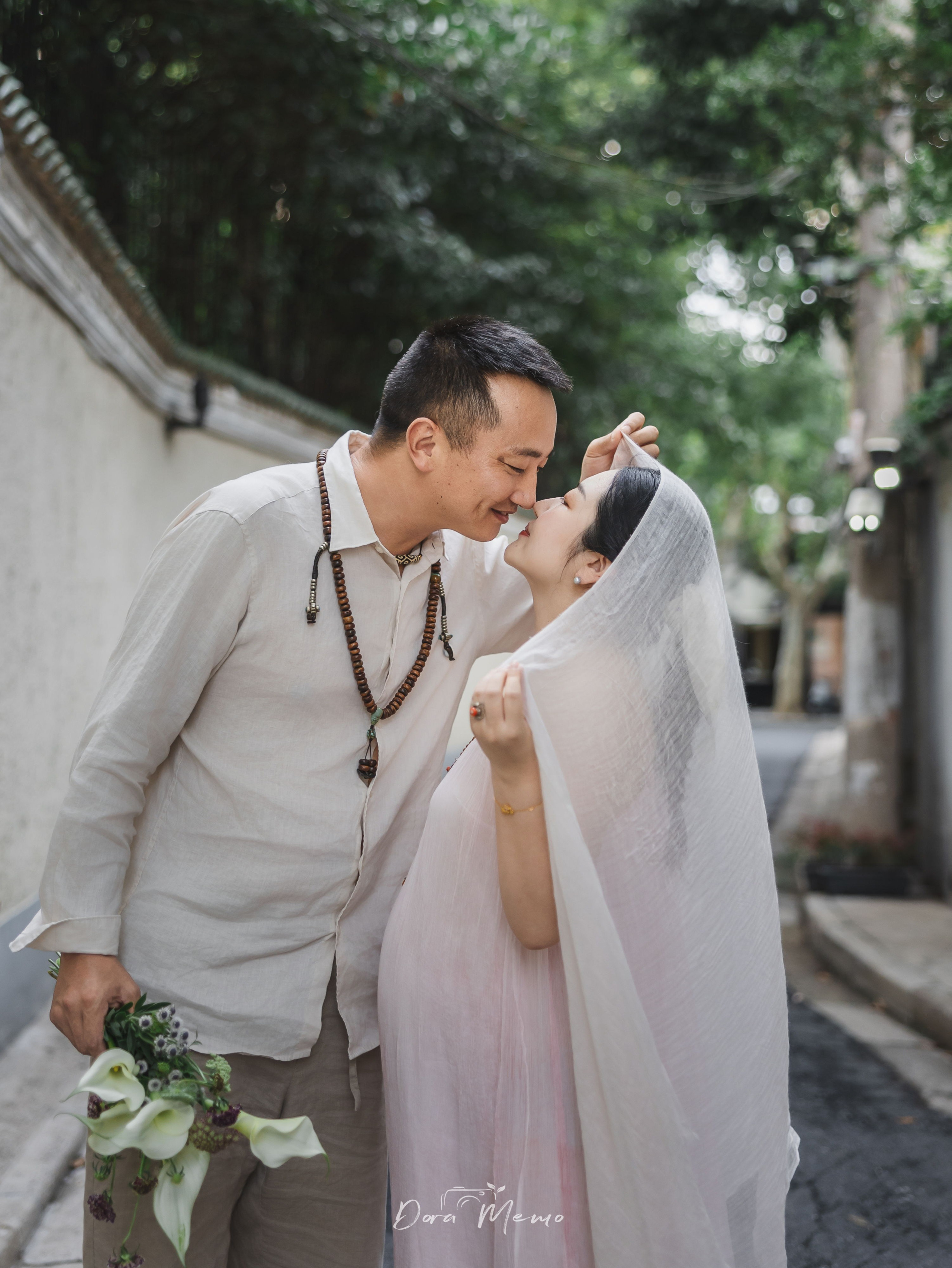 Expecting couple sharing an intimate kiss on a quiet street, photographed by a Shanghai family photographer in a natural documentary style.