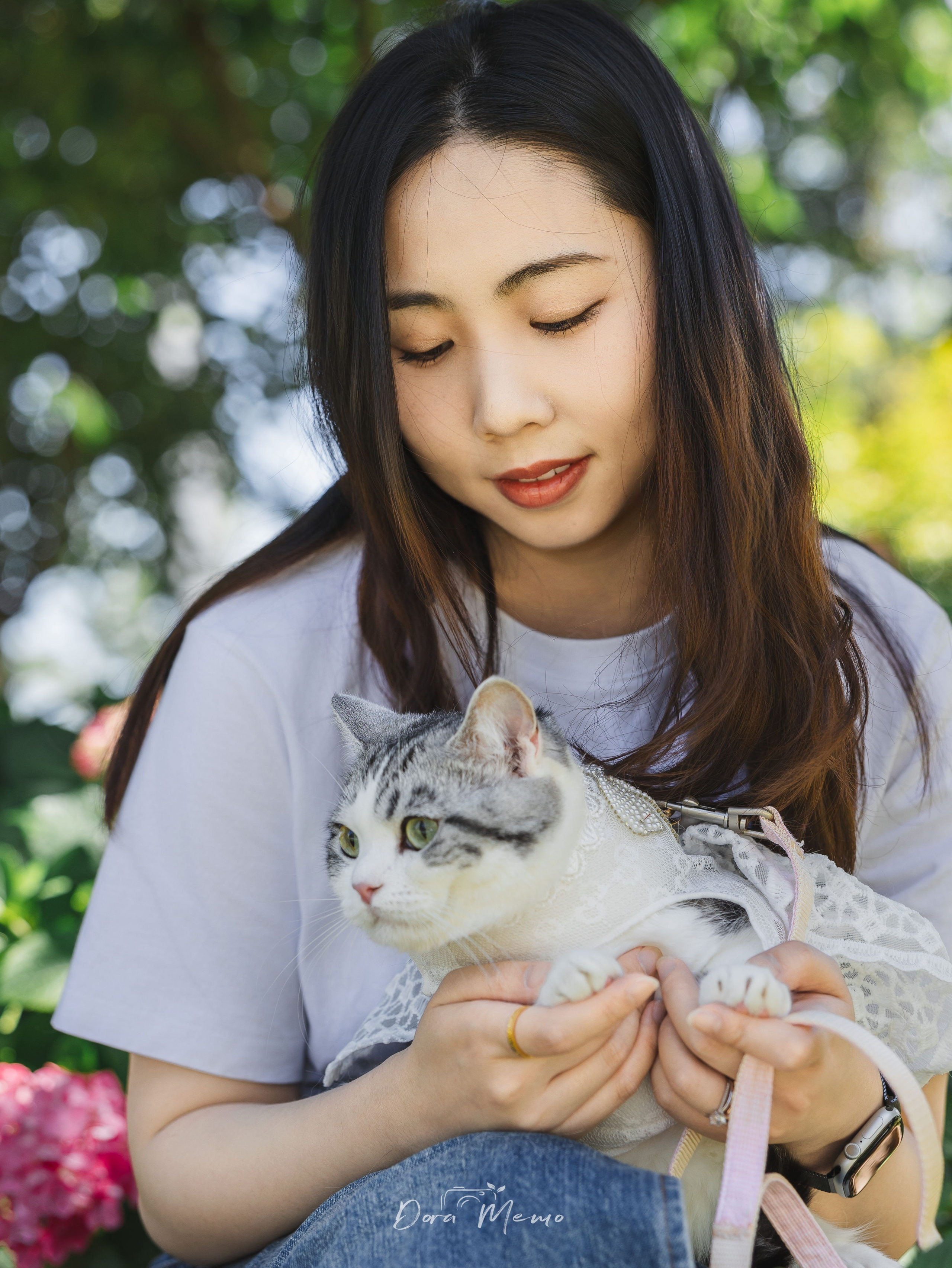 Woman gazing tenderly at her cat while holding her close, soft outdoor portrait 