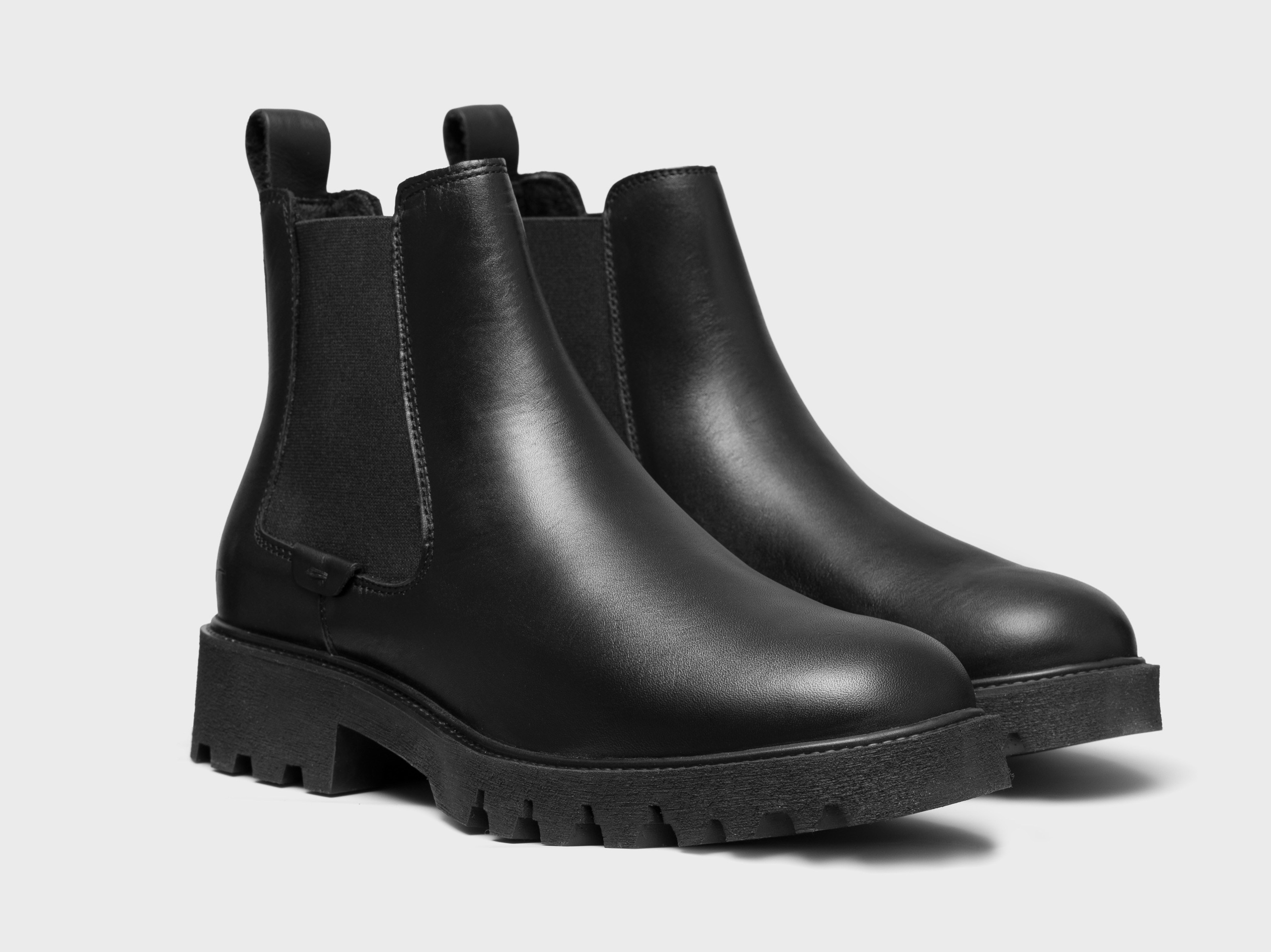 Black leather Chelsea boots white background front view product photography