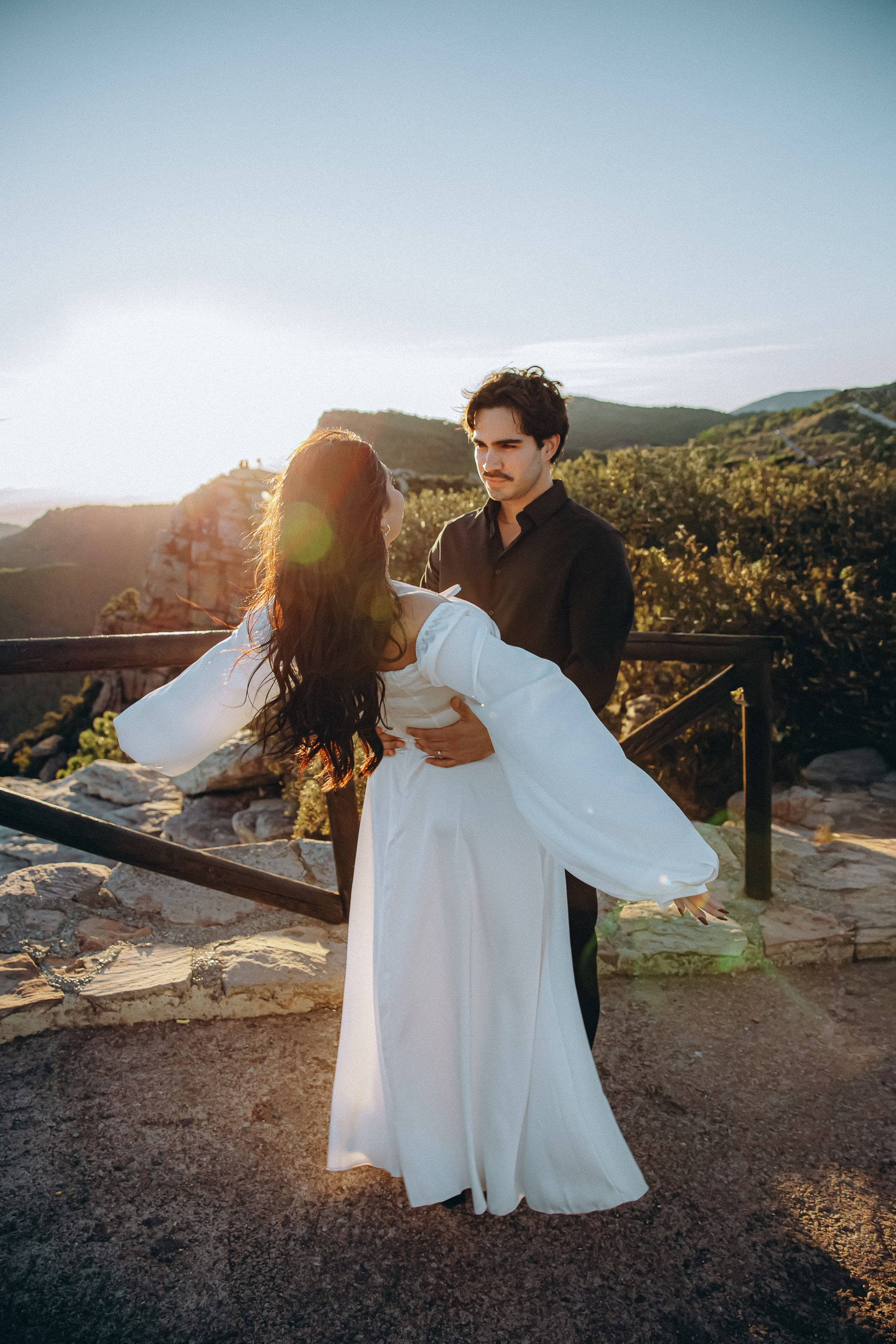 Bride and groom dancing on a mountain terrace during a sunset destination wedding in Barcelona, Spain. The flowing dress and open landscape highlight the freedom and intimacy of a private elopement celebration.