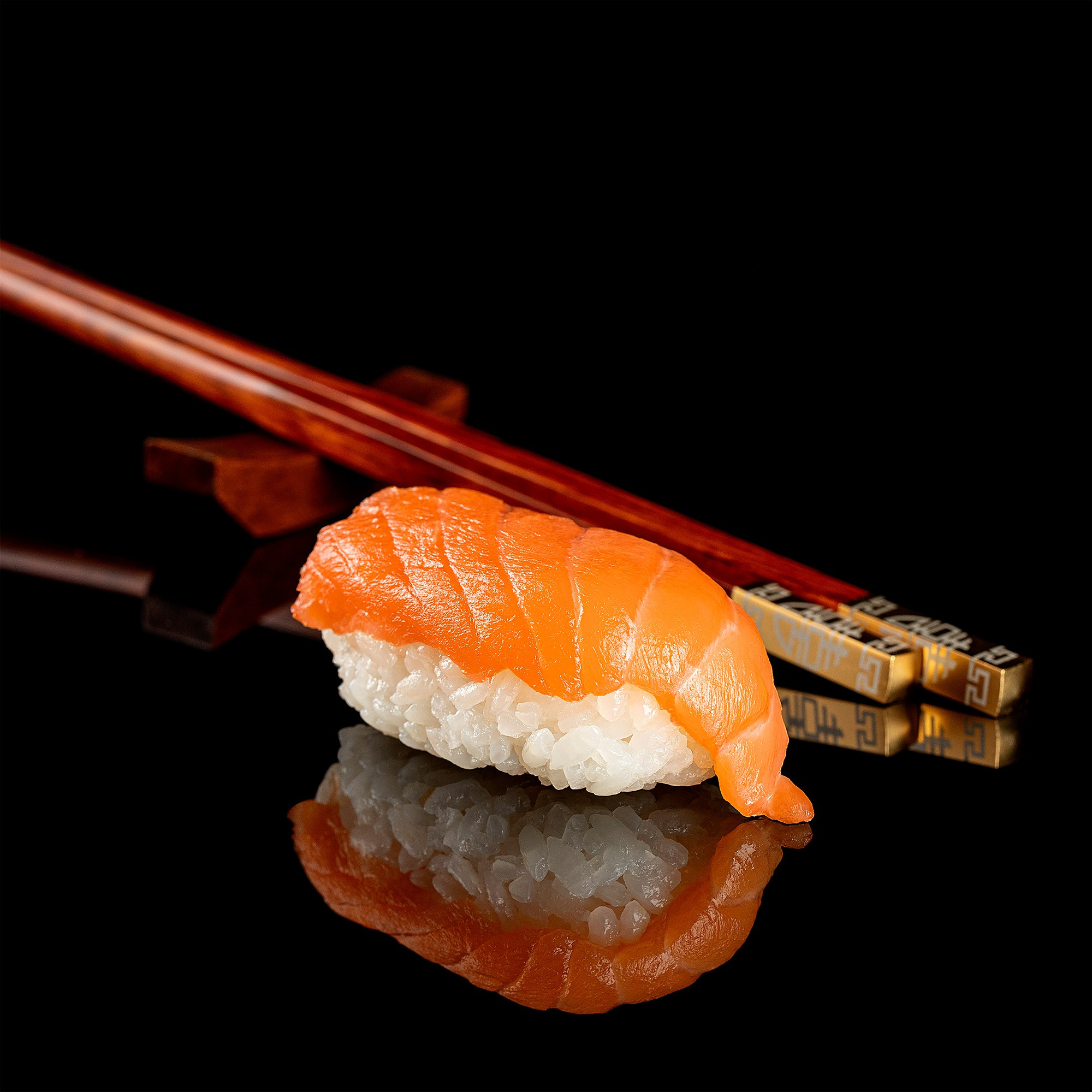 Photographer Roman Djuzev - Sushi Nigiri with salmon with chopsticks on a black acrylic background.
