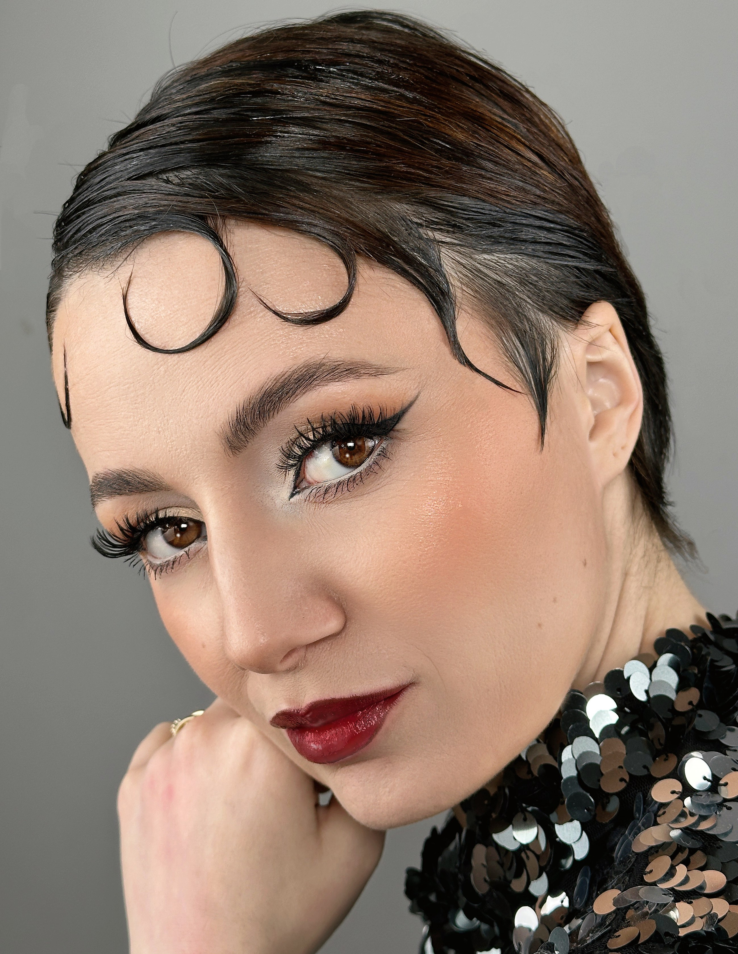 „Machiaj retro glam iconic inspirat din anii '50, cu eyeliner cat-eye, buze roșii intense și ten impecabil. Un look clasic și elegant pentru evenimente speciale.”