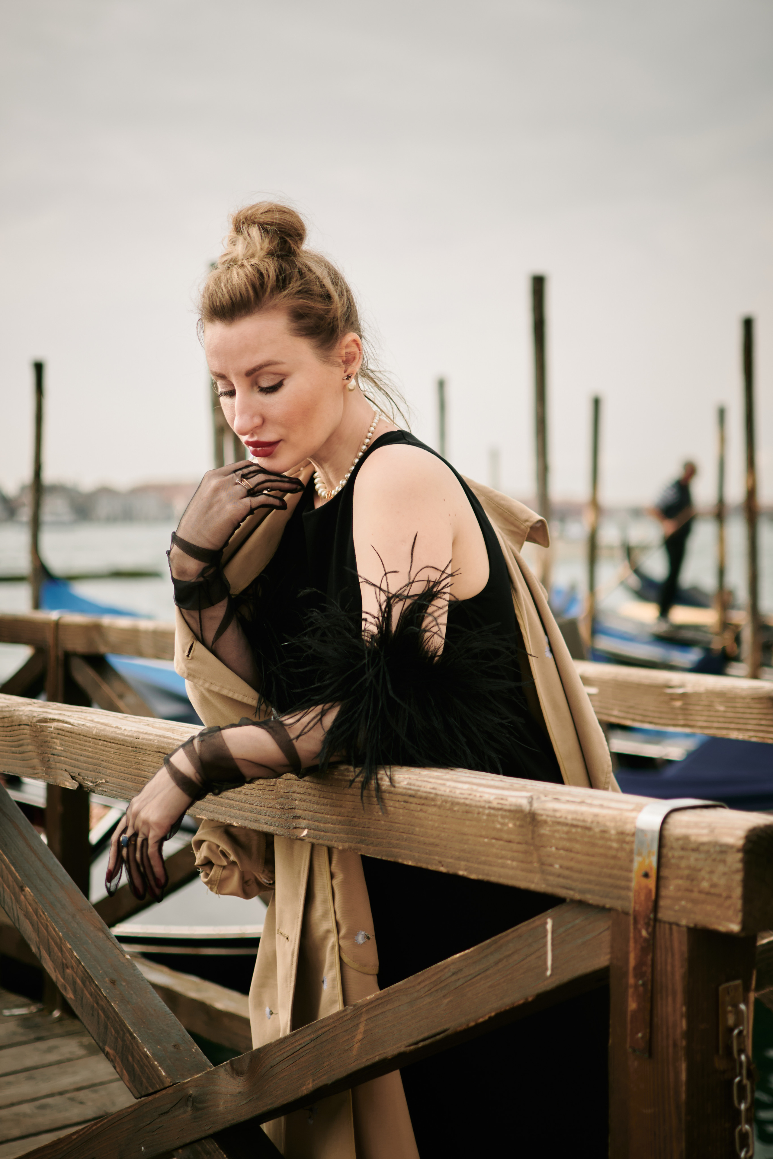  this stunning portrait, a young woman in a black dress stands on a narrow bridge, gazing out at the panoramic view of San Marco Square in Venice. The bridge's elegant arches frame her perfectly, adding a touch of architectural interest to the scene. A woman stands by the water's edge in Venice, Italy. She cradles her growing belly with one hand and gazes out at the stunning view of the city's canals and historic buildings. The soft light of the sun sets behind her, casting a warm glow on her face and highlighting the intricate lace of her dress. The quiet beauty of the moment is captured in this serene portrait, as the woman awaits the arrival of her precious little one