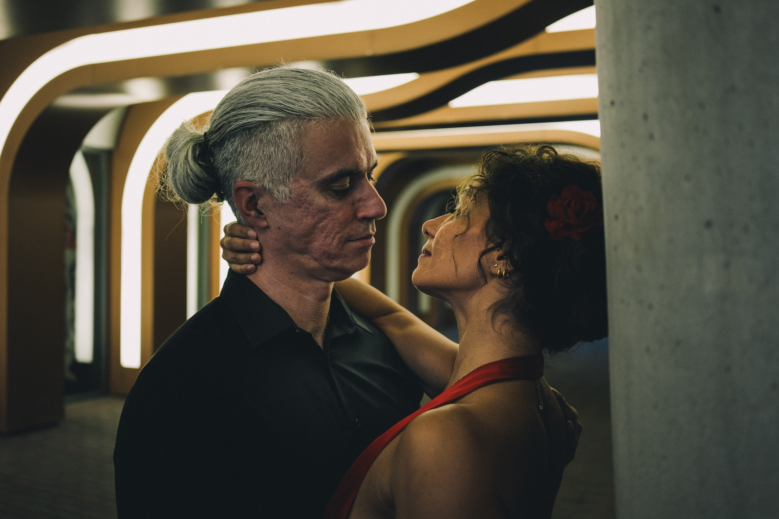 Couple dancing on a quiet street under string lights — celebrating their upcoming wedding
