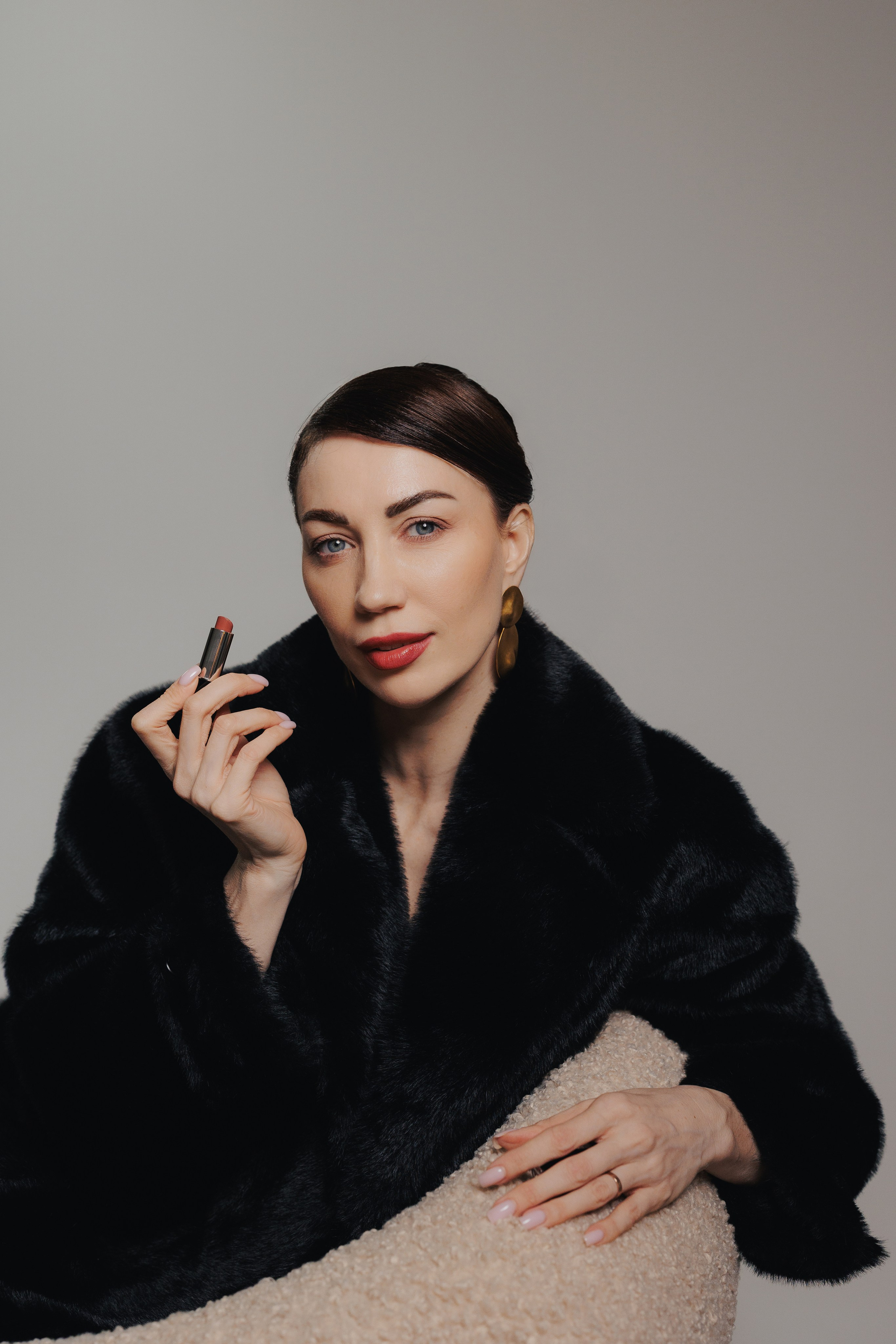 Elegant editorial studio portrait of a woman in a black fur coat touching her face in soft dramatic lighting, photographed in Leipzig, Germany. Элегантный редакционный студийный портрет девушки в чёрной шубе, касающейся лица, в мягком драматичном свете, снятый в Лейпциге, Германия.