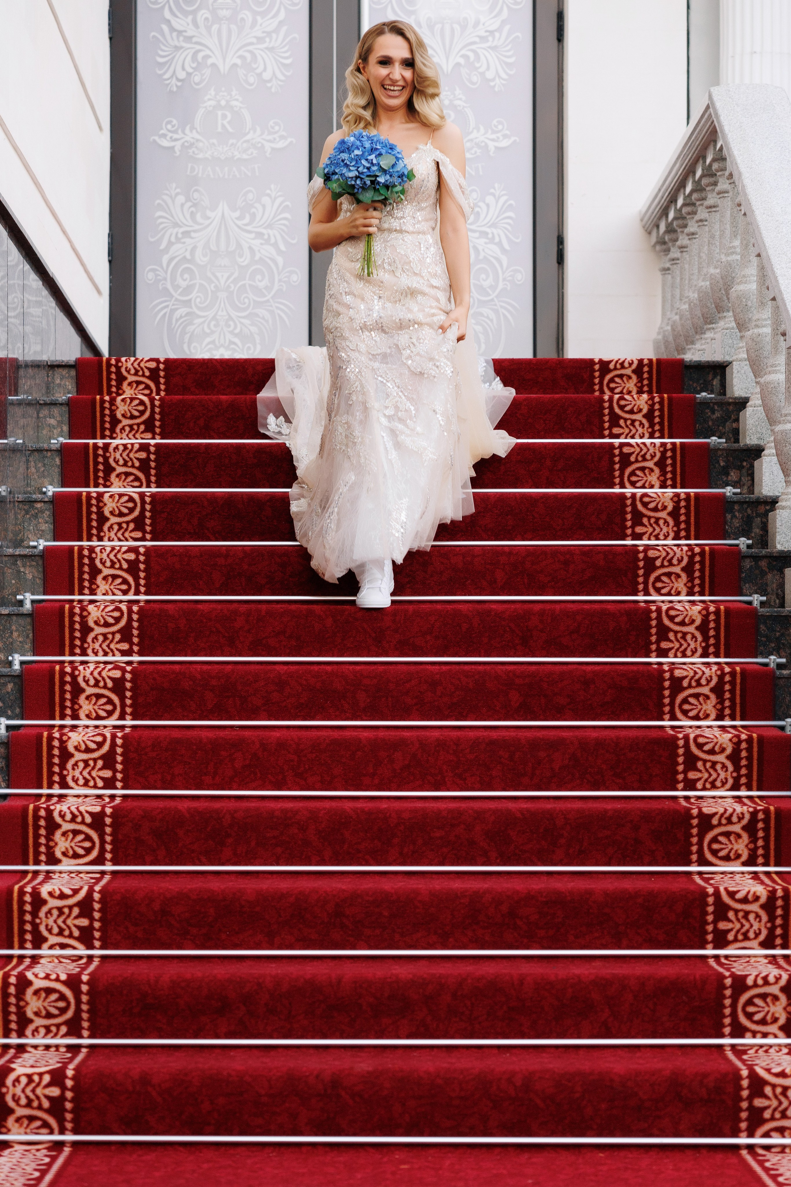 mireasa coboară pe scări și covorul roșu către mire