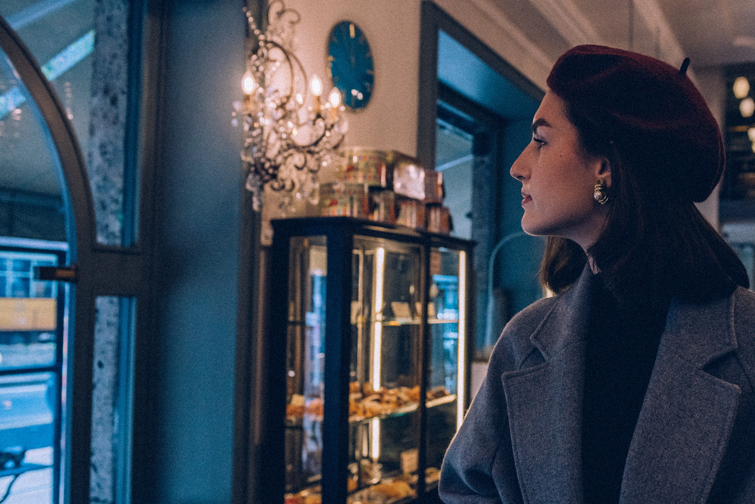 Charming Milanese setting with a fashionable woman gazing through the cafe window, surrounded by warm lighting and vintage decor. Milan photographer for tourists