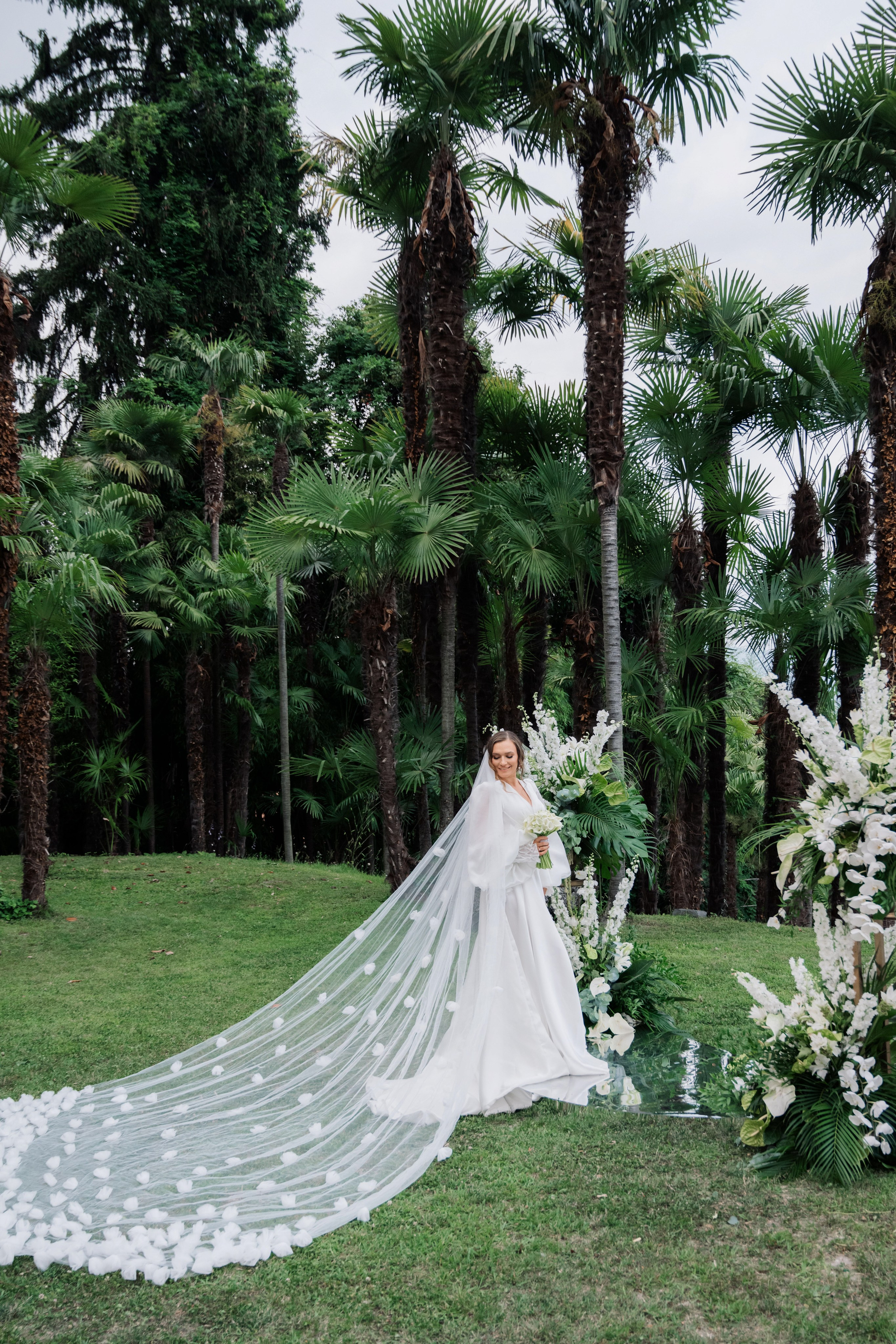 a bride in a wedding dress standing in front of palm trees