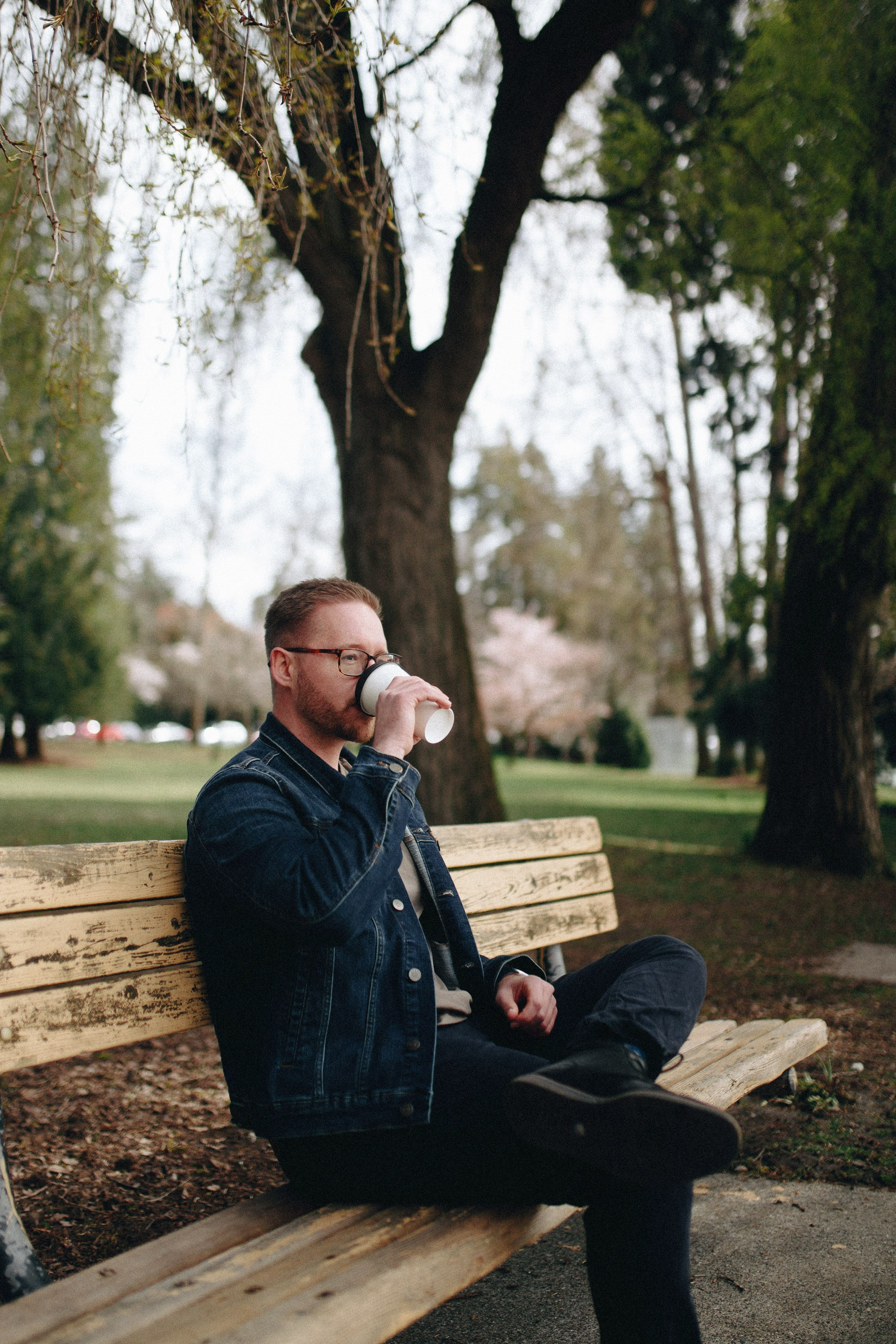 Man in black sweater sitting under tree outdoors