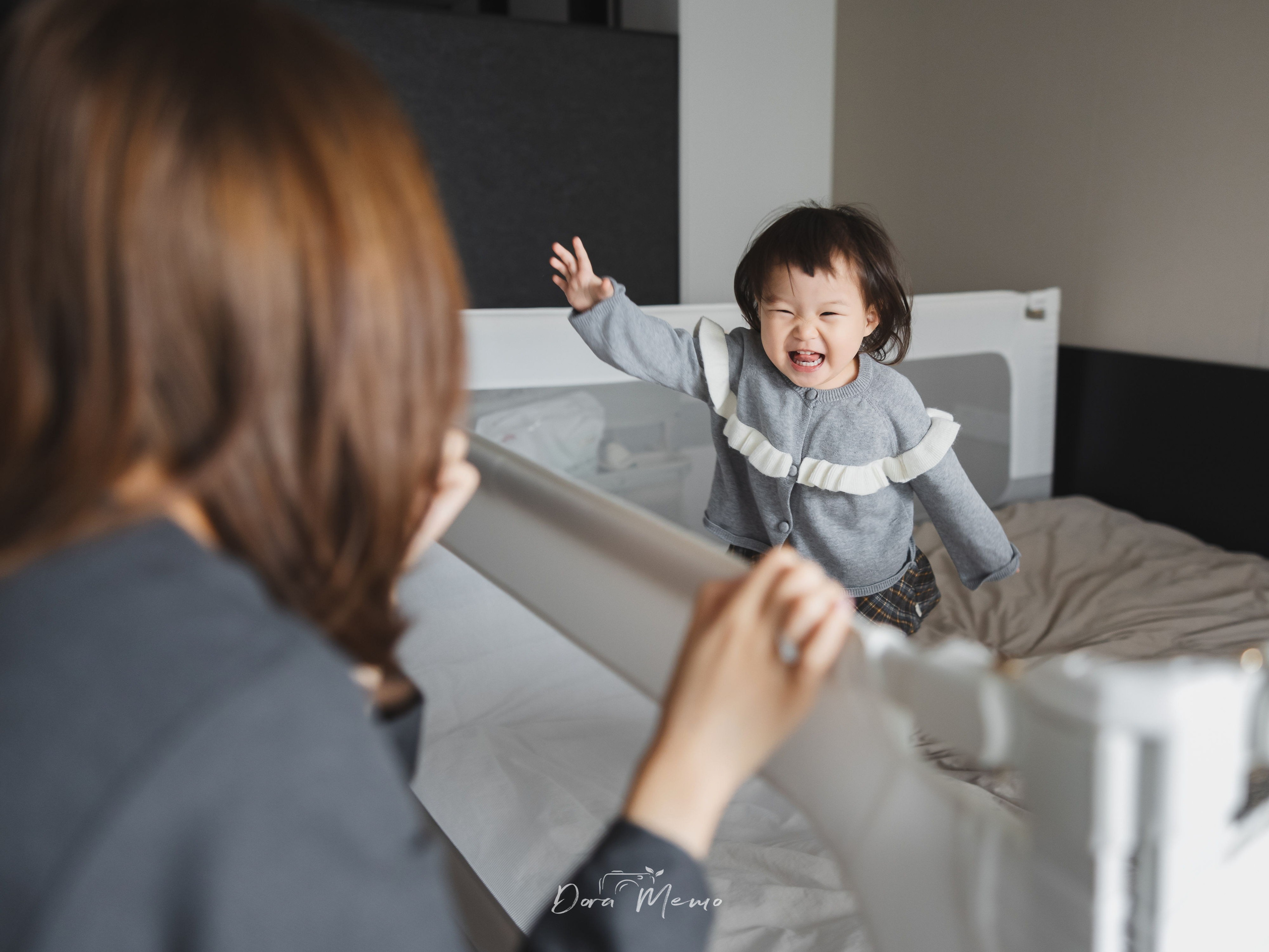 Close-up of a two-year-old girl laughing on the bed, candid moment captured during a family photo session in Shanghai.
