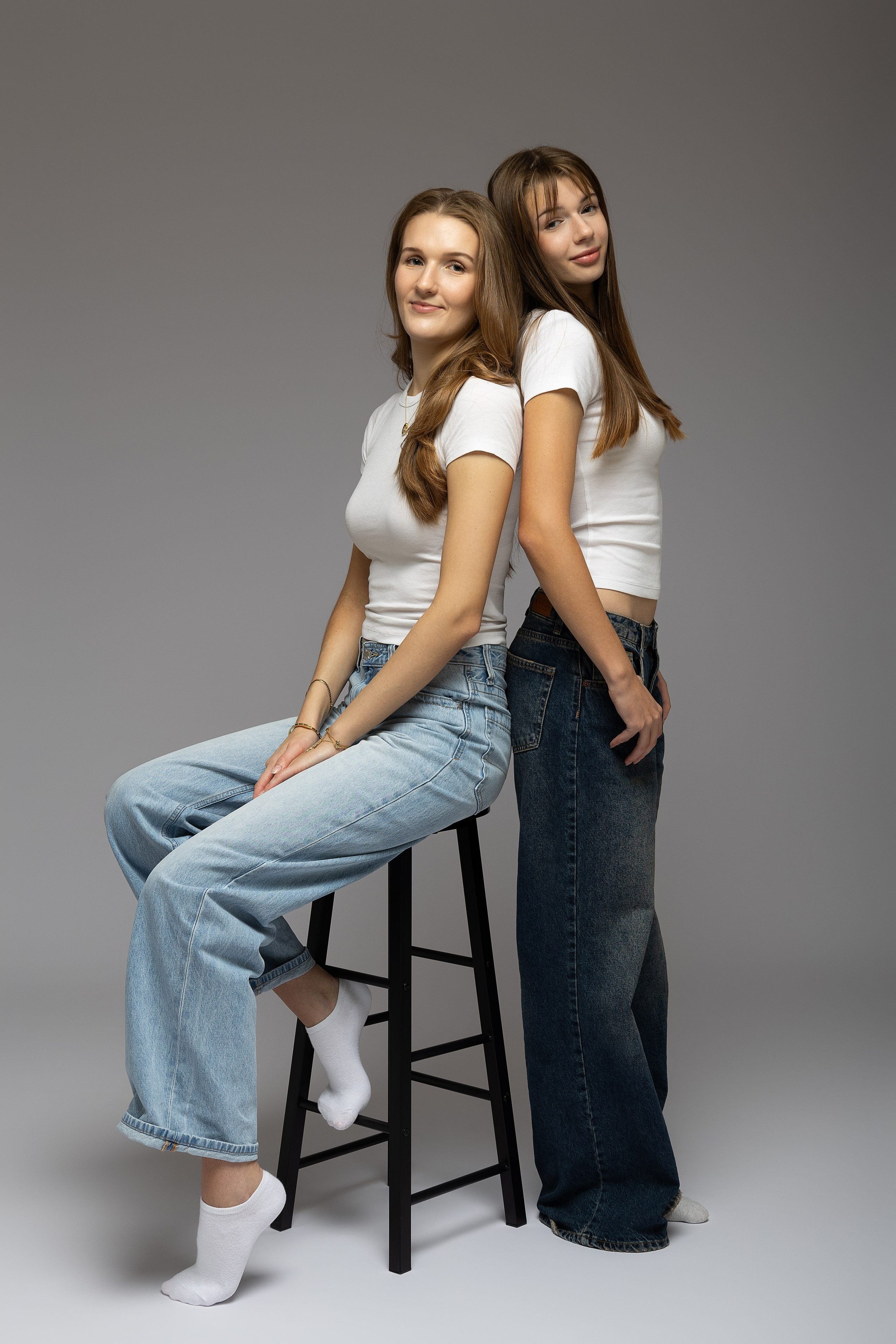 Zwei Schwestern stehen eng beieinander im Studio und blicken ruhig in die Kamera