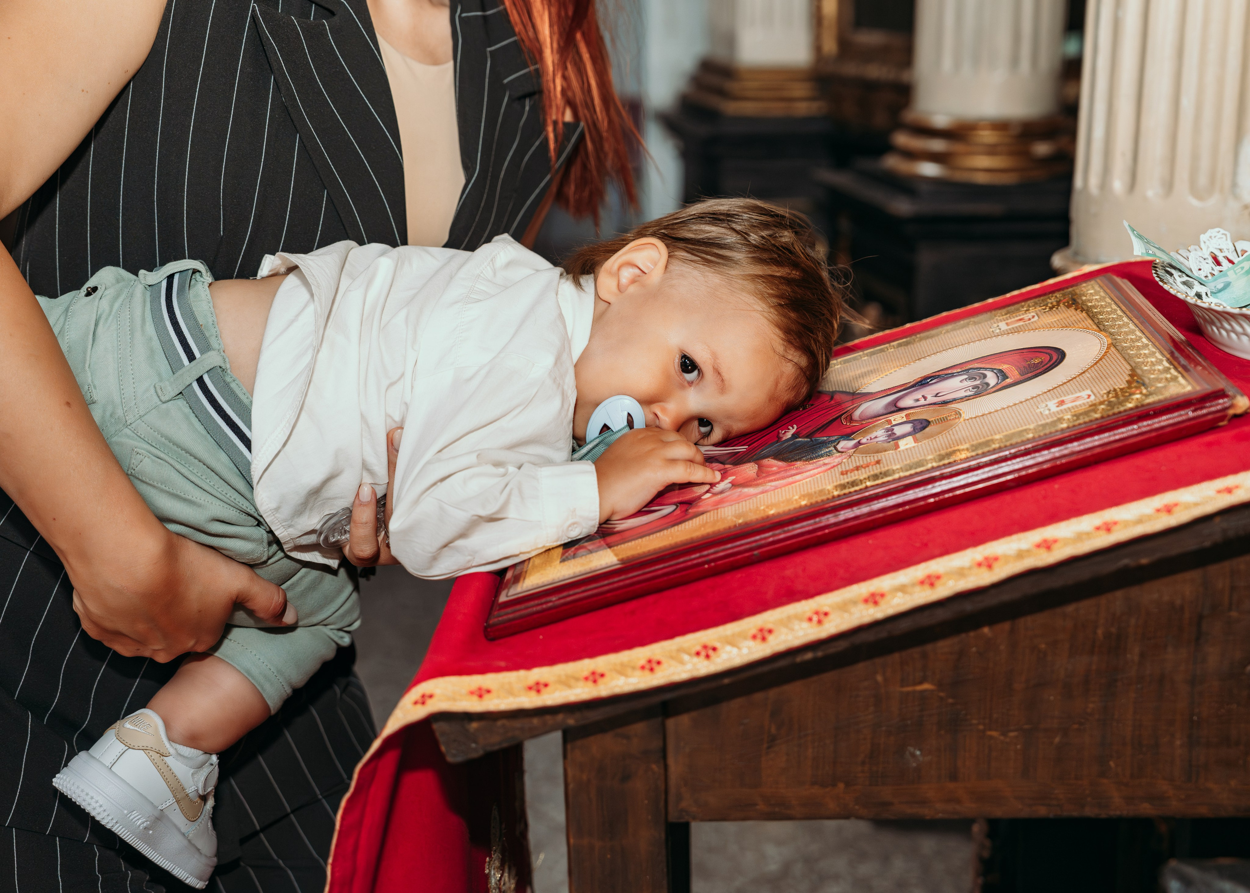 Krštenje bebe uz ikonu i krst u crkvi