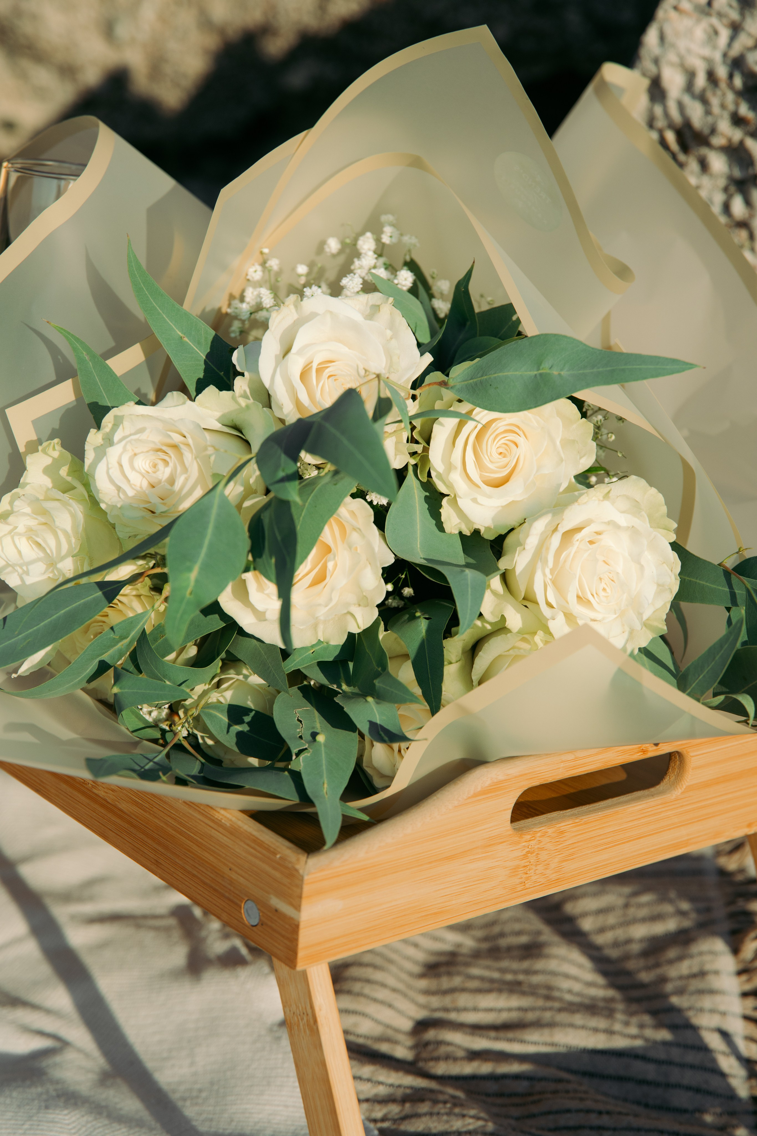 "Zeitlose Eleganz: Ein Strauß weißer Rosen als Symbol der Liebe bei einer Verlobung auf Rhodos, eingerahmt von azurblauem Wasser und hellem Kalkstein."