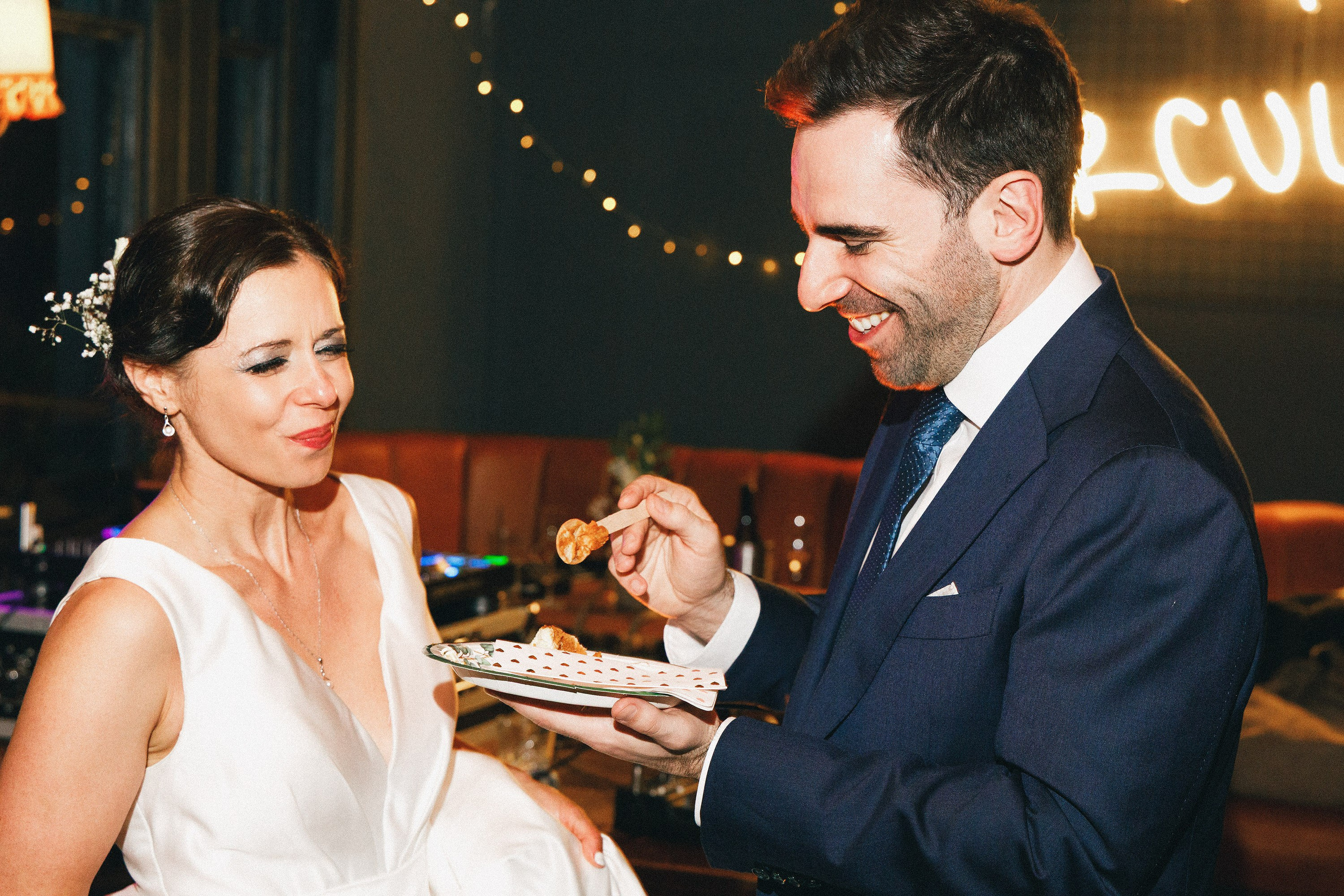 Newlyweds sharing a bite of cake at their London pub wedding