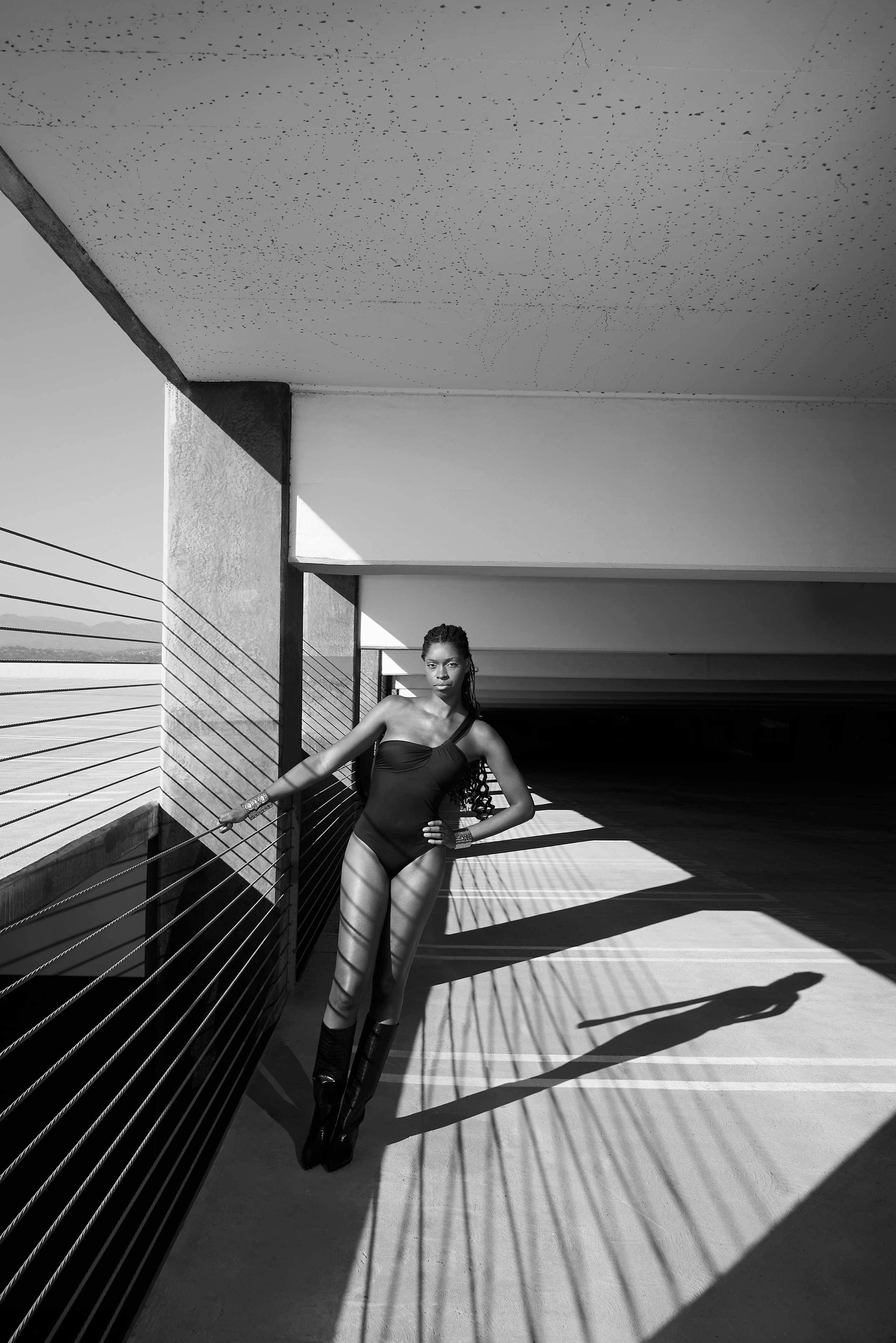 Woman in high boots standing confidently under strong sunlight.
