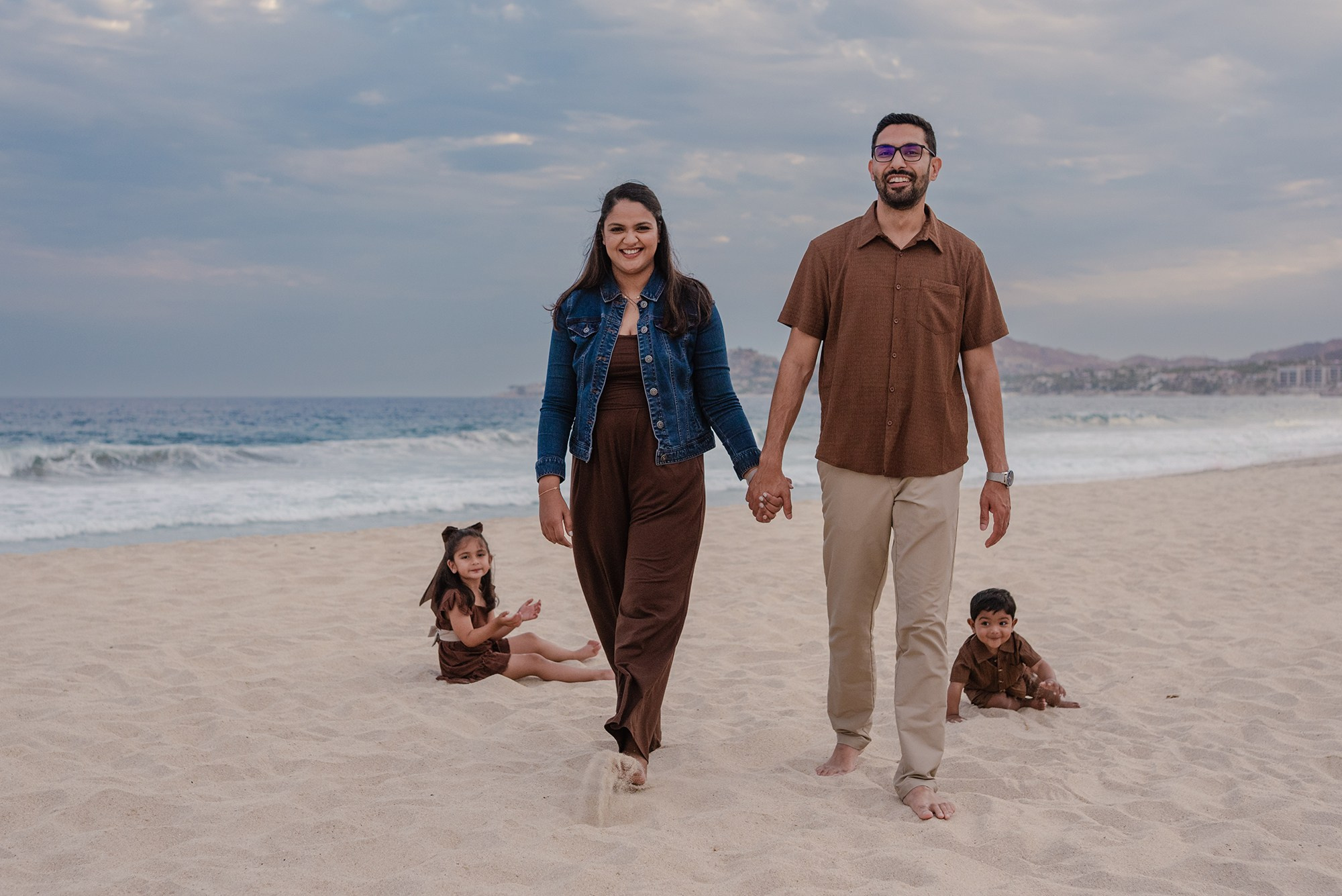 Family of four walking hand in hand along the beach at Hyatt Ziva Los Cabos