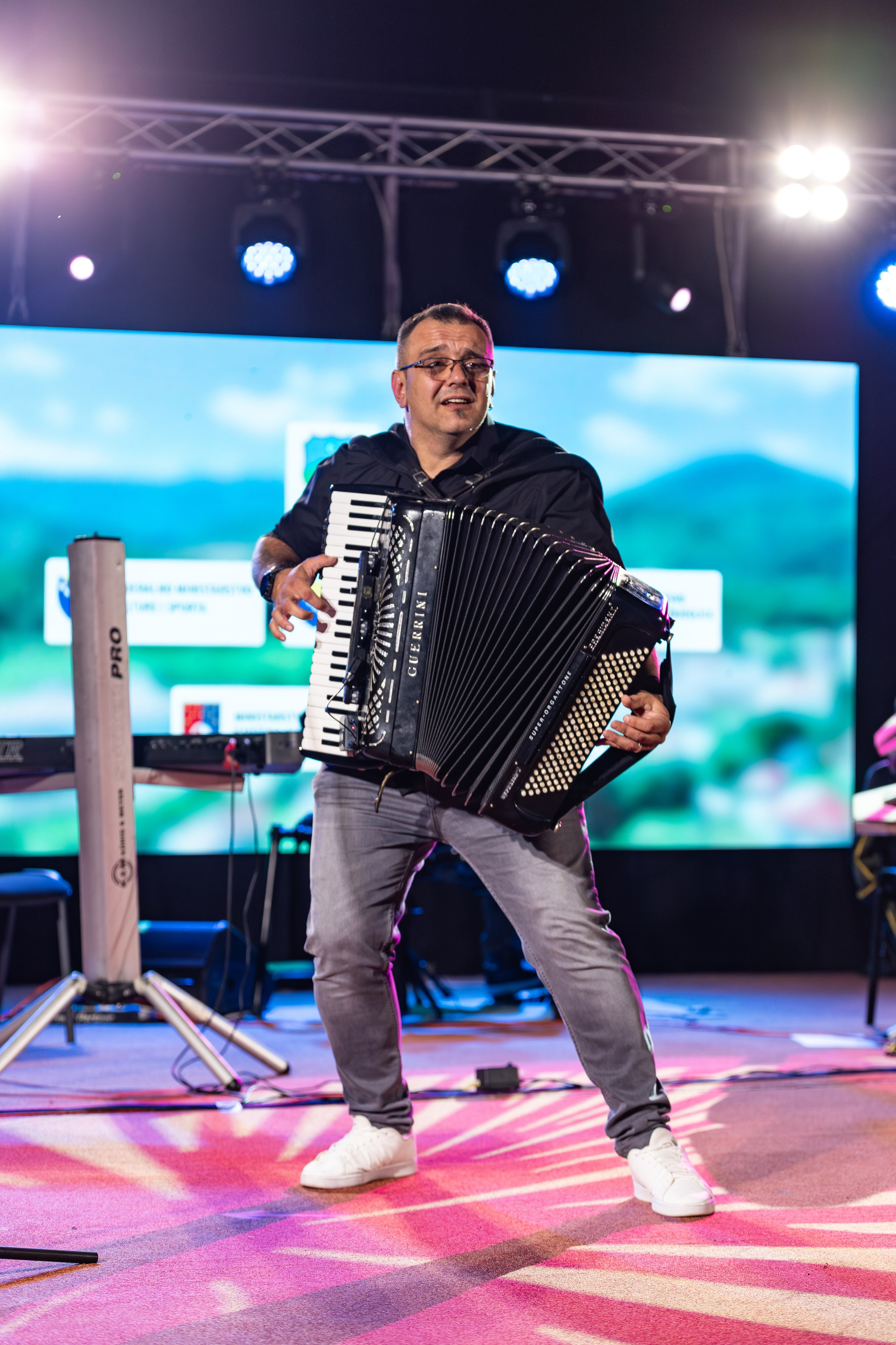 Fotografije takmičenja pjevača amatera na festivalu Tarčinske ljetne večeri u organizaciji KUD-a Ivan Planina, prikazuju nastupe učesnika na pozornici, scensku rasvjetu i atmosferu festivala.
