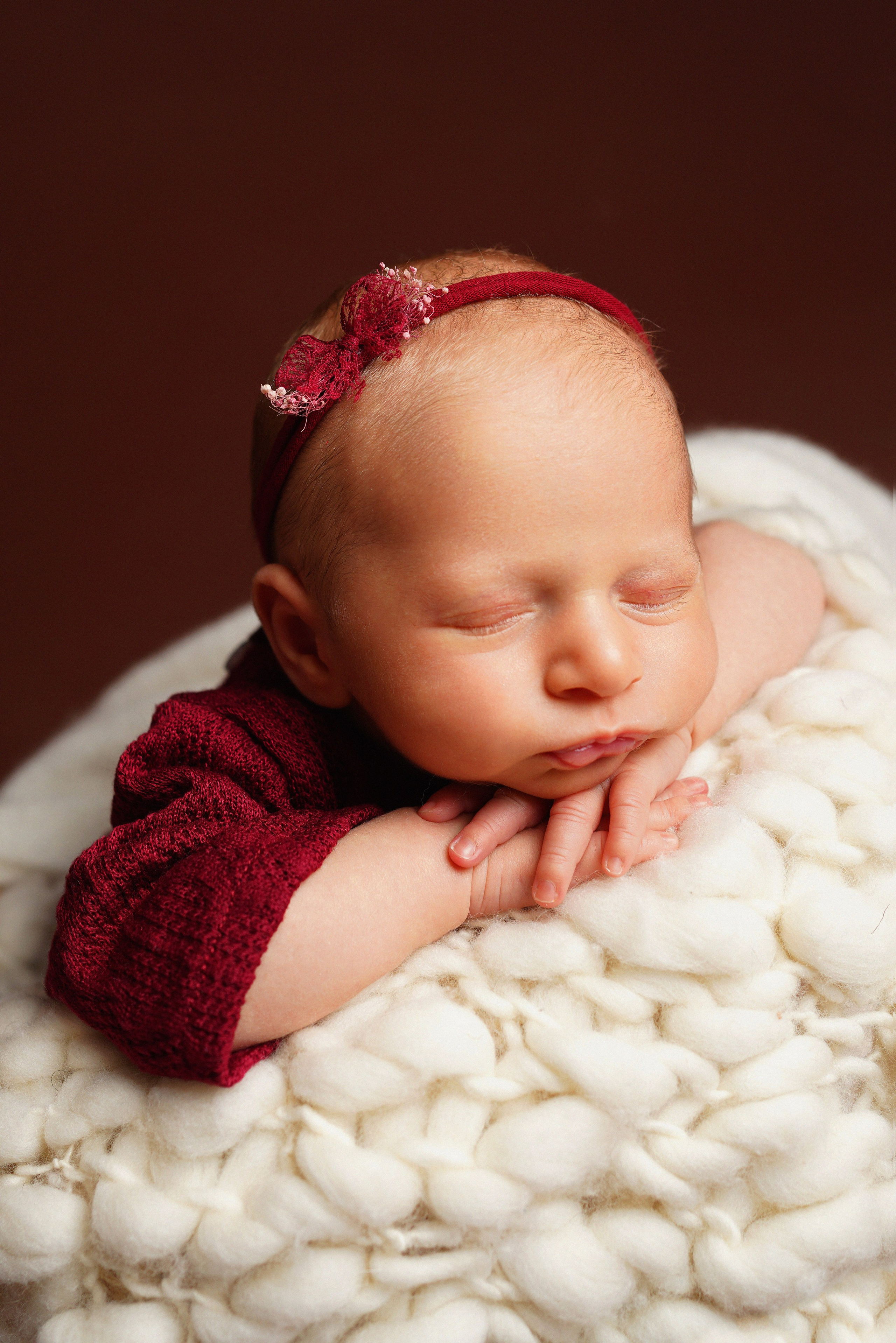 Mädchen in einem bordeauxfarbenen Kleid mit einer Schleife auf dem Kopf