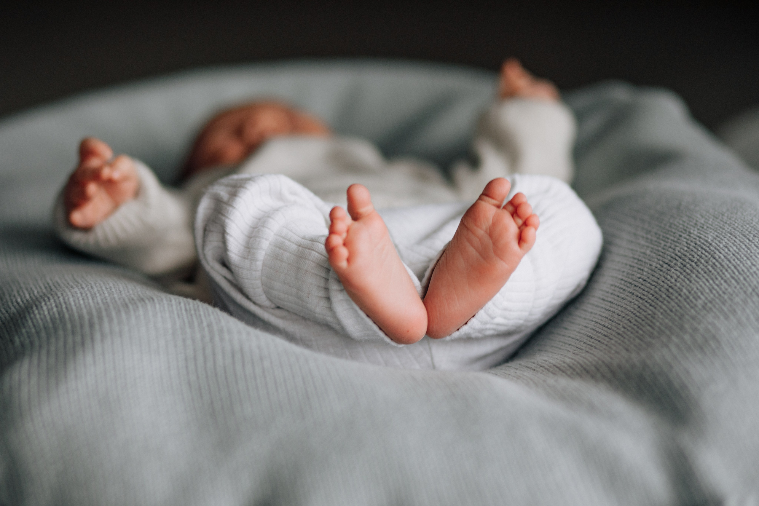 Kleine Babyfüße liegen in einem geflochtenen Korb. Ein süßer und liebevoller Moment.