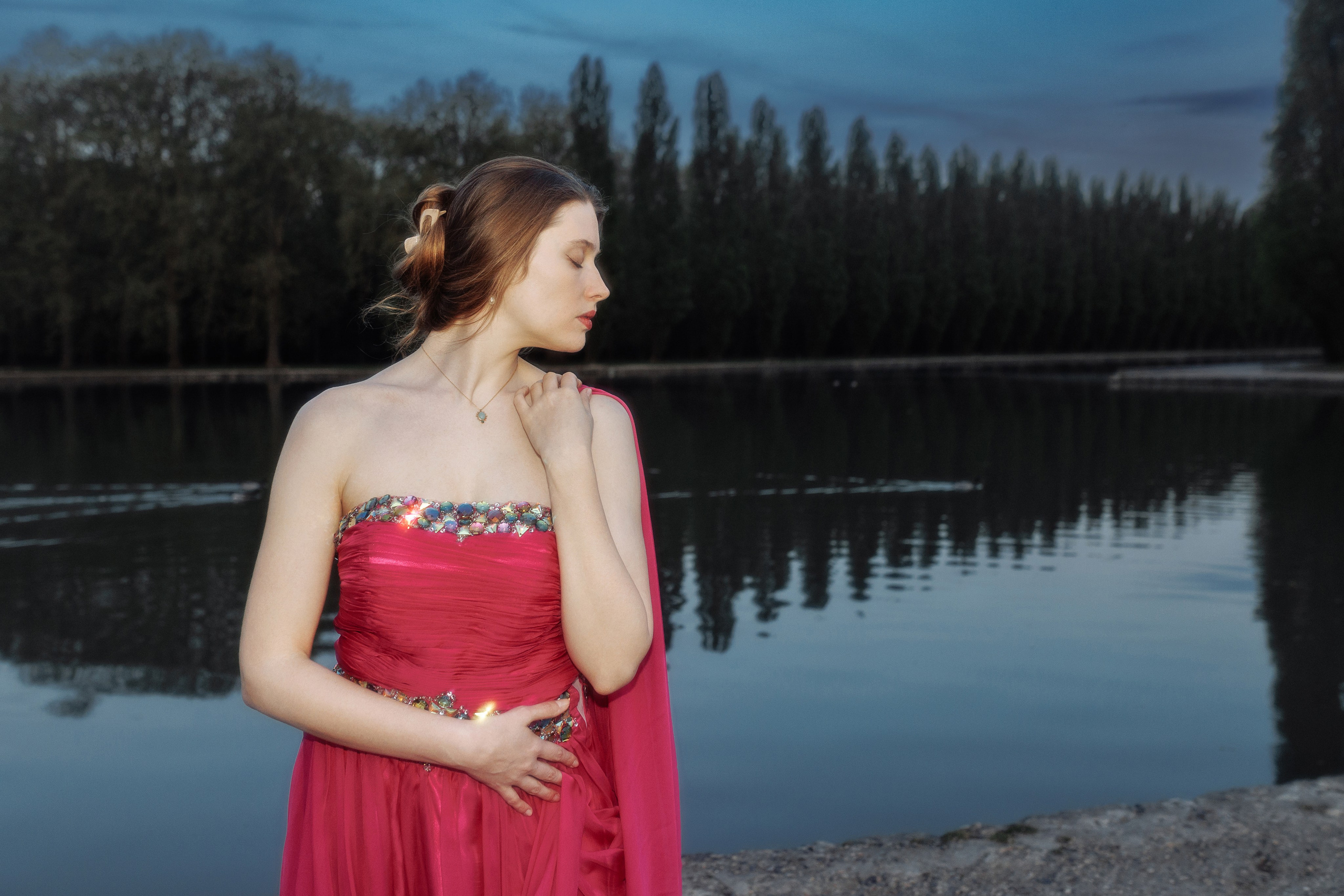 Певица позирует в сумерках среди розовых деревьев