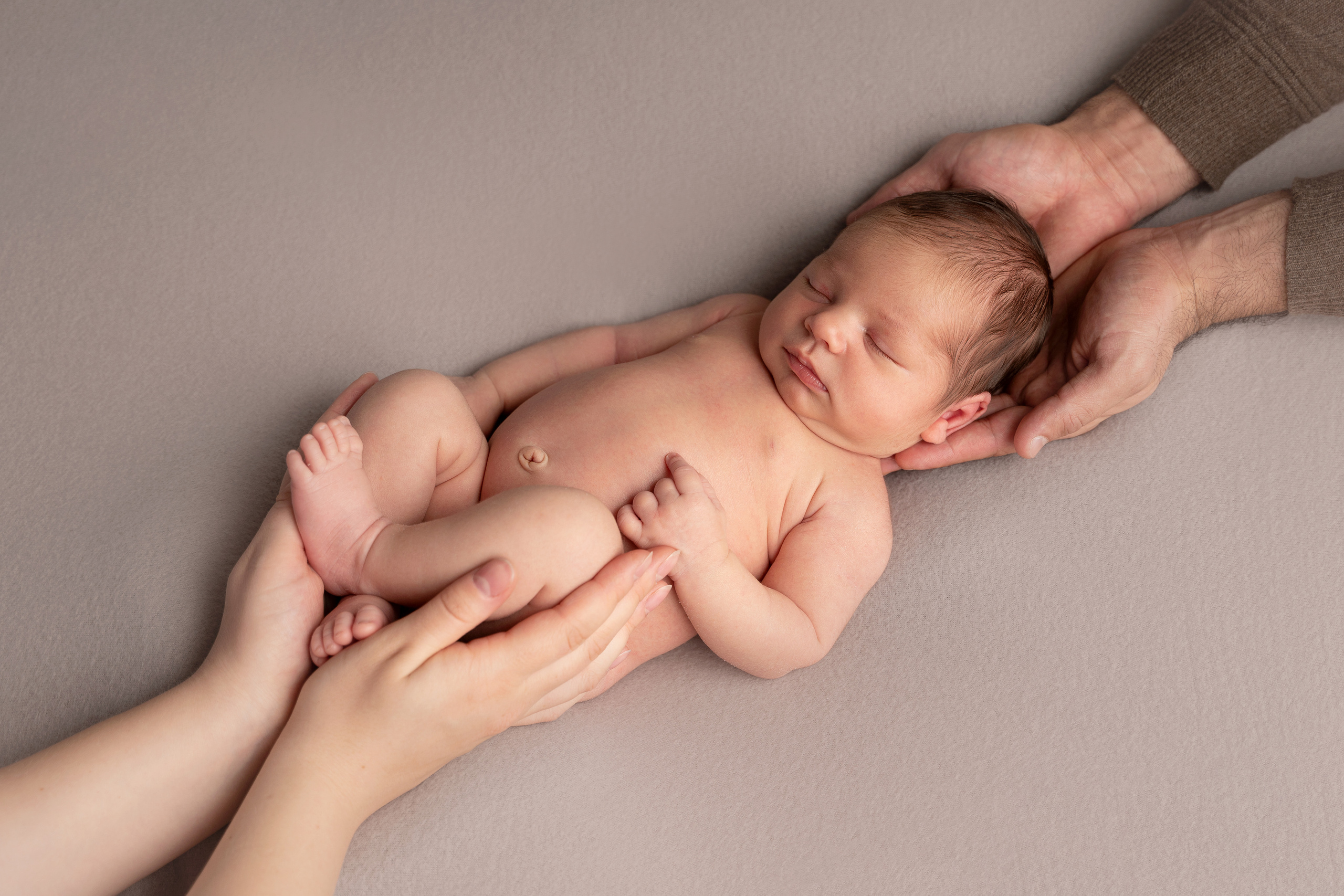 Neugeborenes in den Armen der Eltern nackt