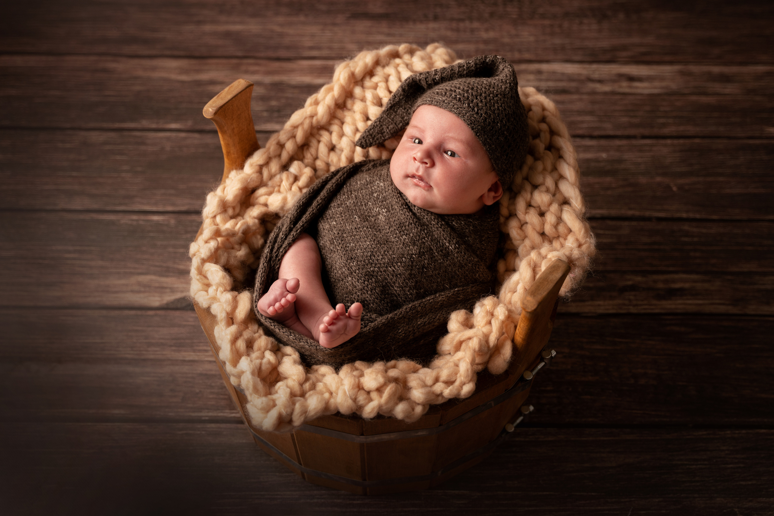 kleinkind posiert auf dem Rücken liegend in braunen Kleidern