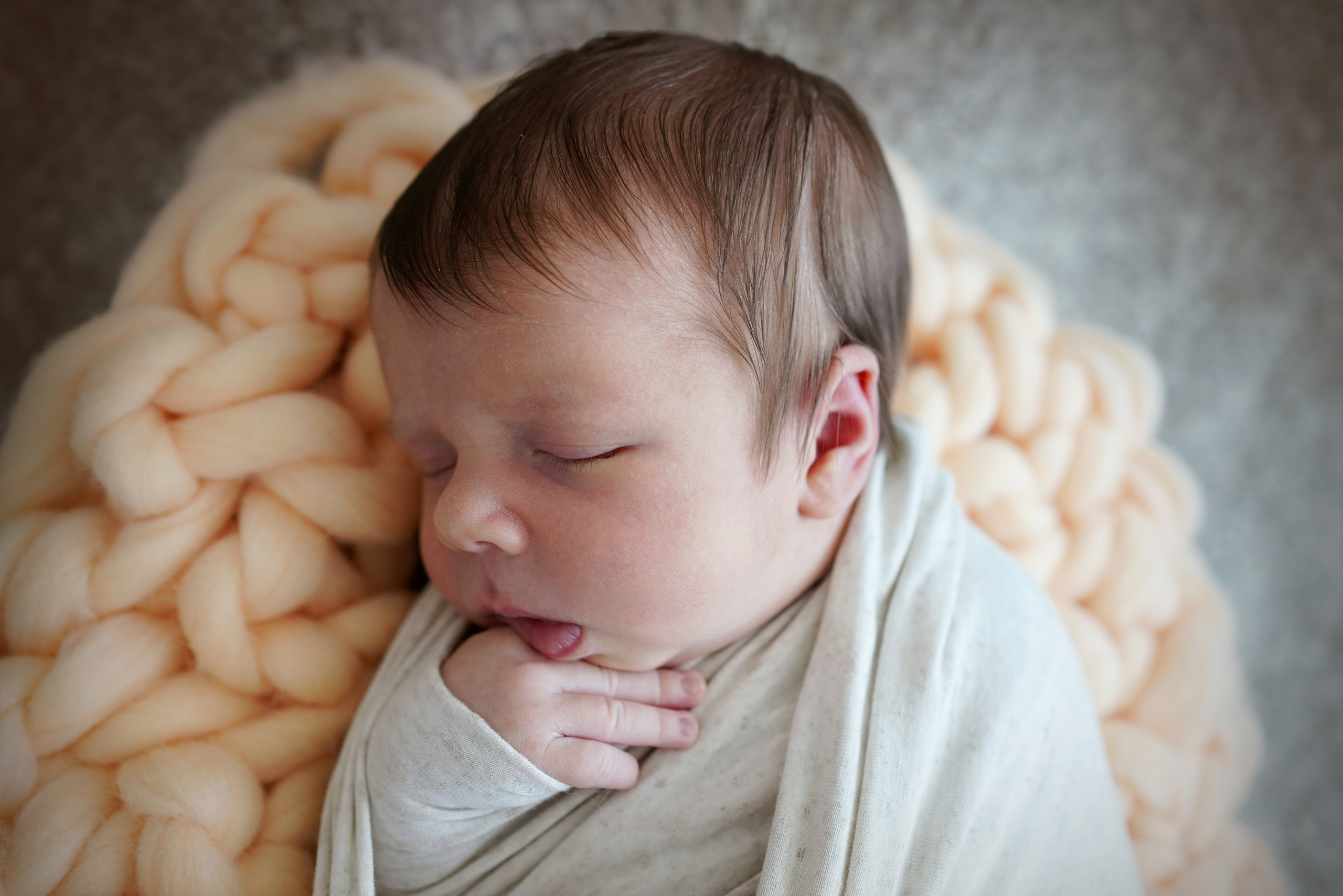 Baby in einer Pose, die einen Stift unter dem Kinn hält